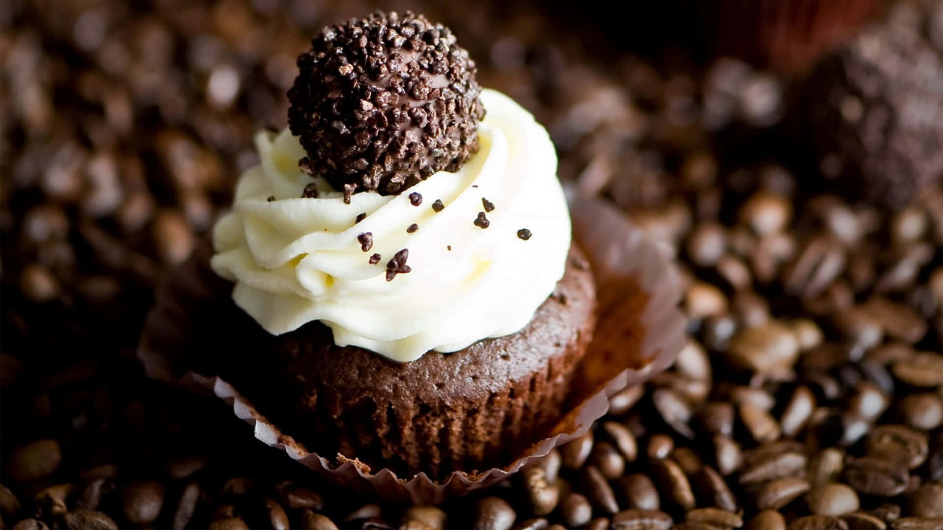 A Cupcake With A White Frosting On Top Of Coffee Beans
