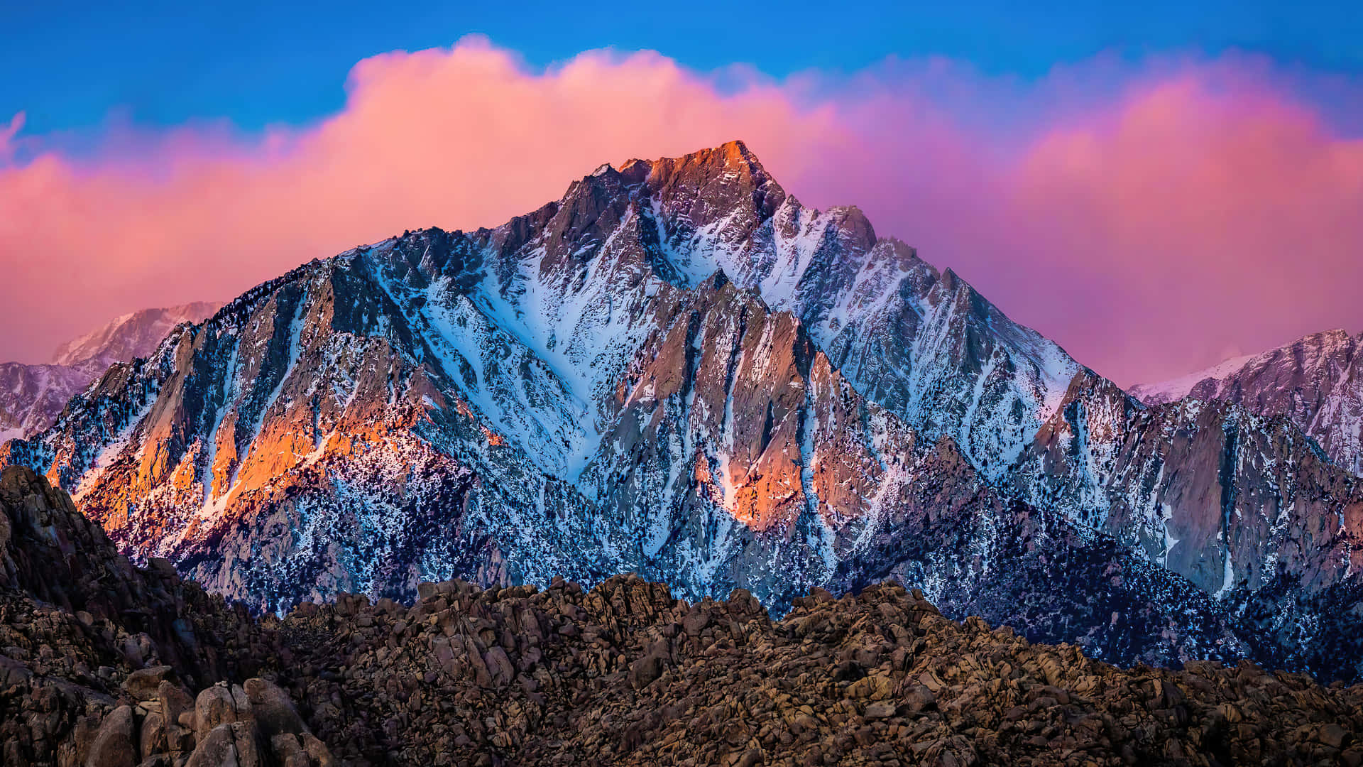 En bjergkæde med en lyserød himmel og sneklædte toppe Wallpaper