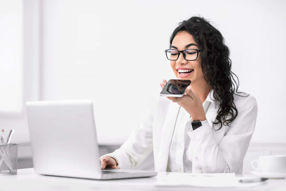 A Woman In Glasses Is Drinking Coffee While Sitting At Her Desk