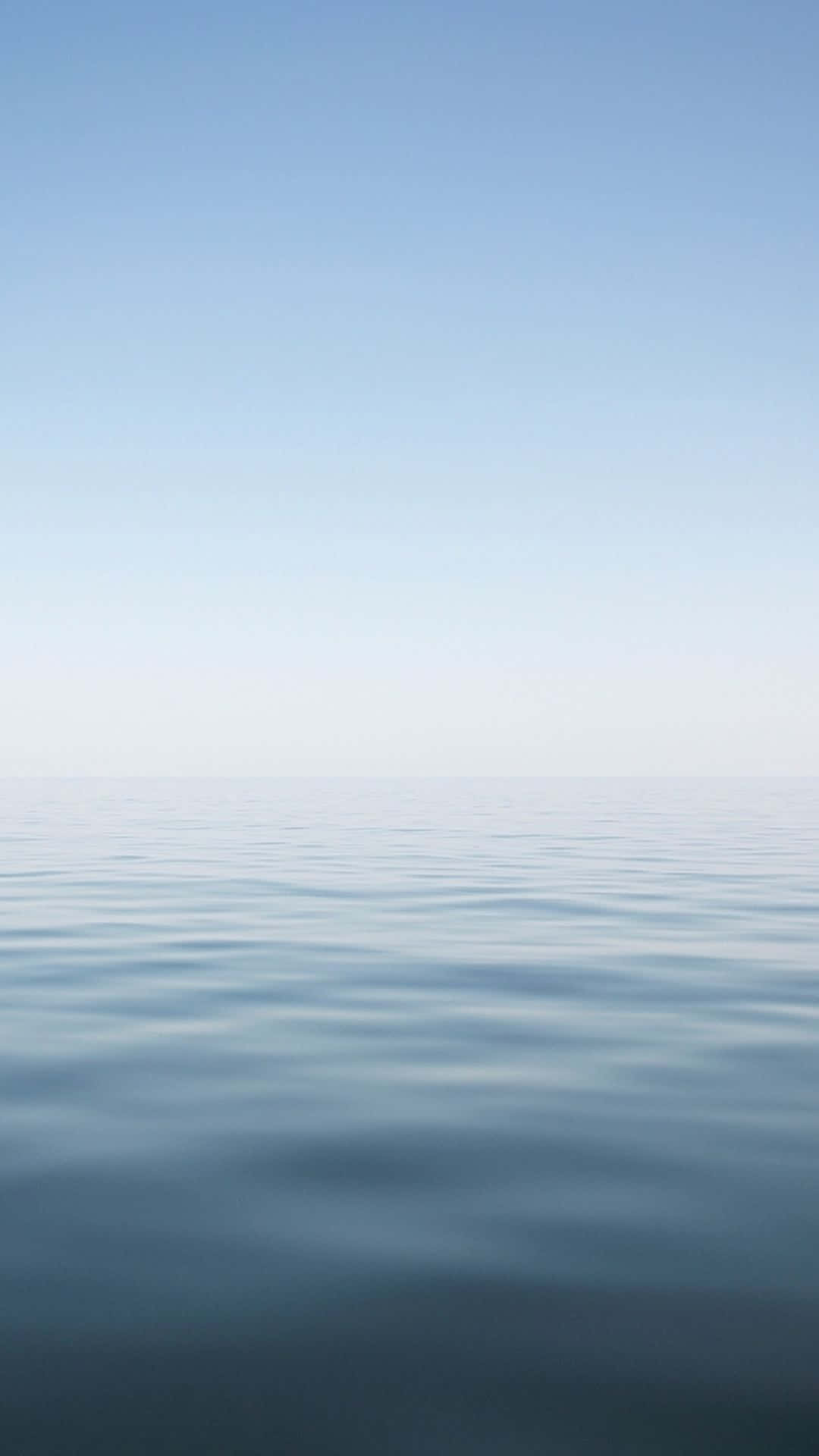 A Blue Ocean With A White Sky Wallpaper