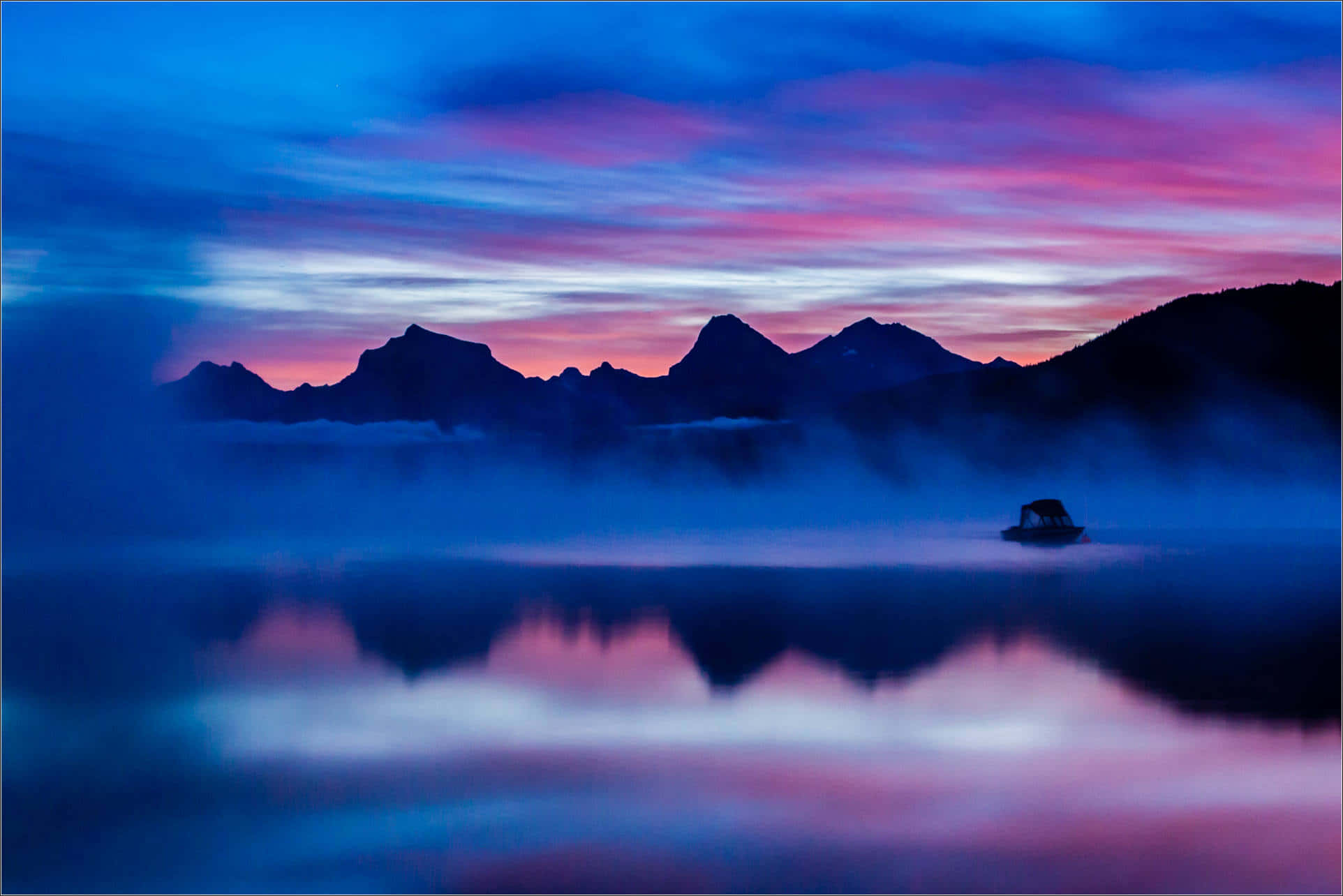 A Lake With Mountains And Fog In The Background