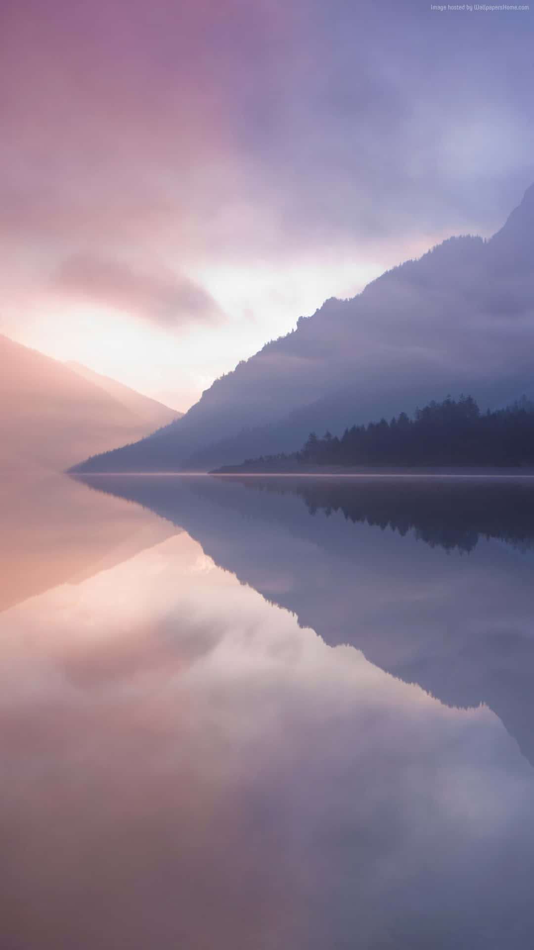 En sø med bjerge og tåge reflekteret i det. Wallpaper