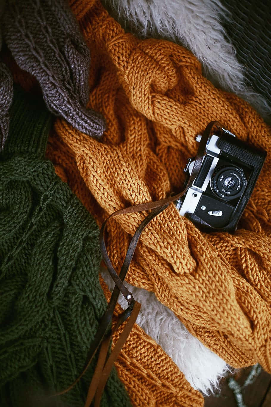 Camera On Top Of A Bronze Colored Knit Sweater Wallpaper