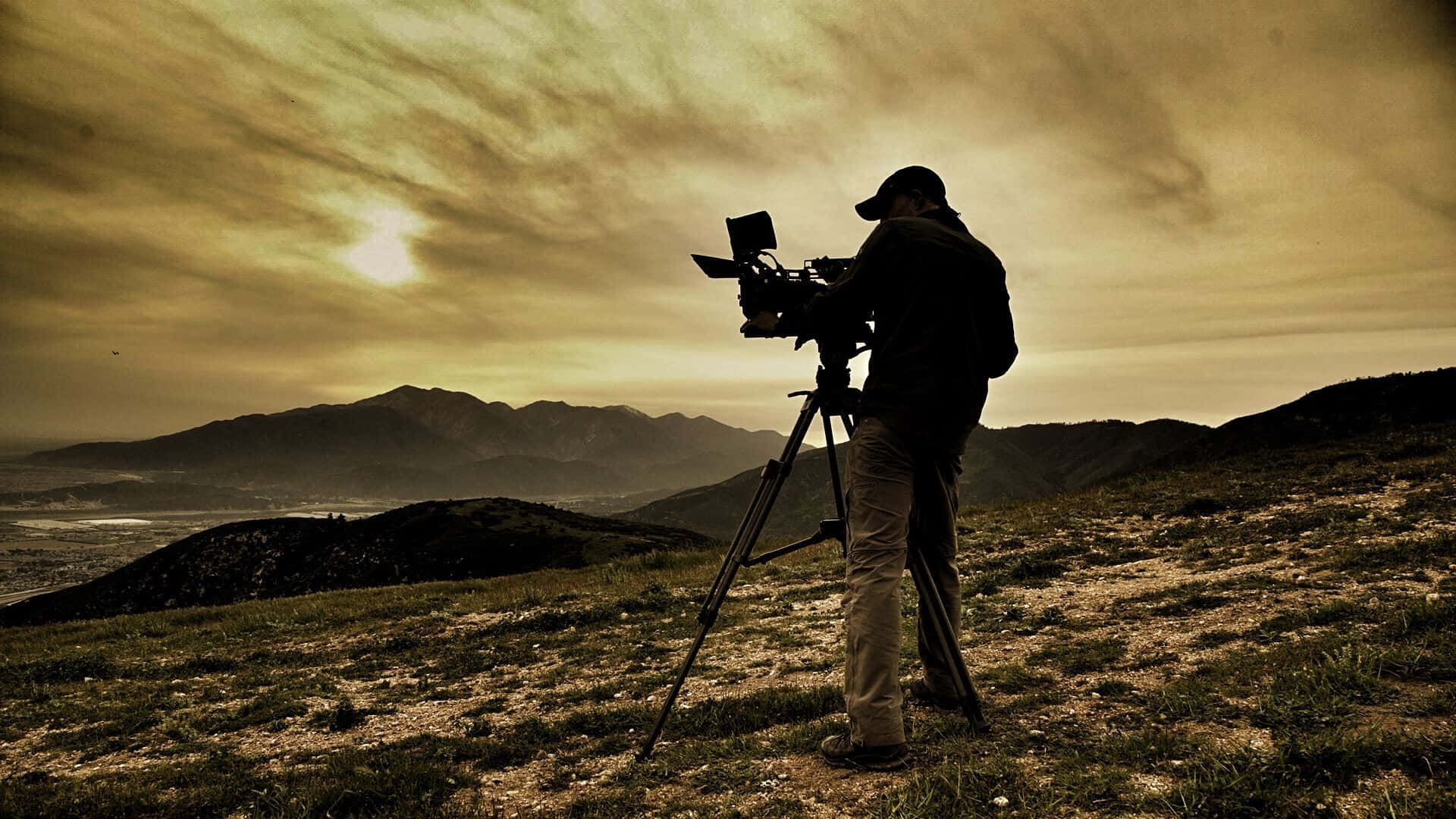 Cameraman_ Capturing_ Sunset_ Mountains Wallpaper