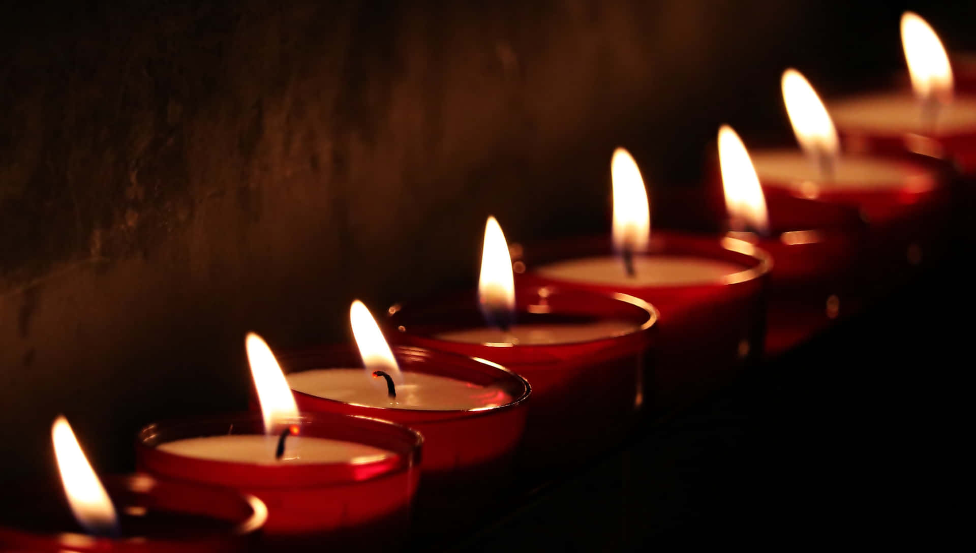 A Row Of Red Candles Lit Up In The Dark