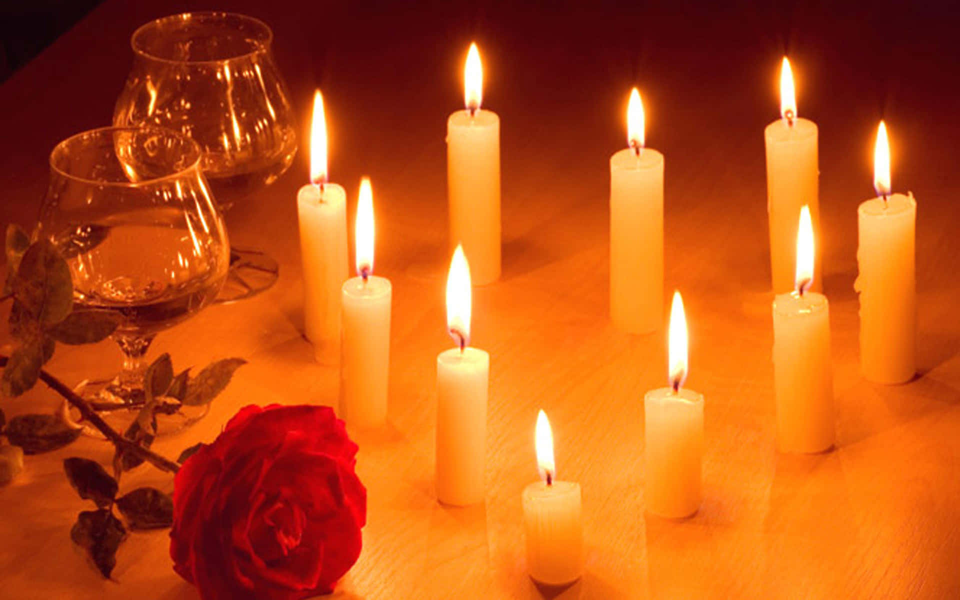 A Group Of Candles And A Rose On A Table