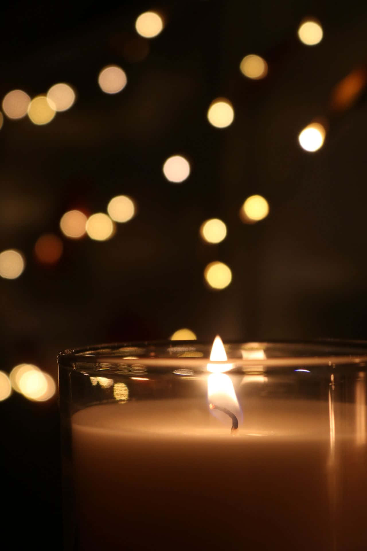 a candle is lit in front of a background of lights