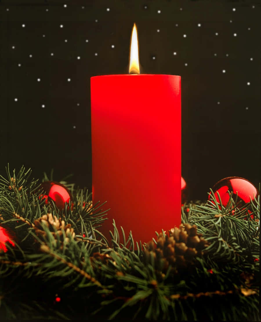 A Red Candle Is Placed In Front Of A Christmas Tree
