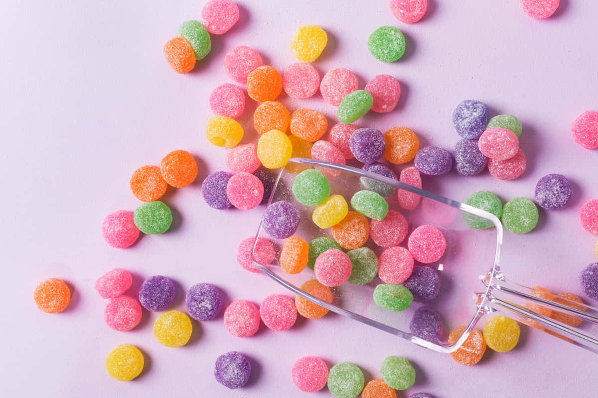 Colorful Candy With A Spoon On A Pink Background