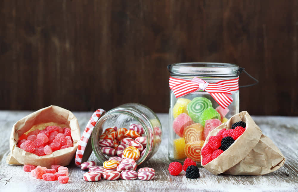A Variety Of Candy In Jars On A Wooden Table