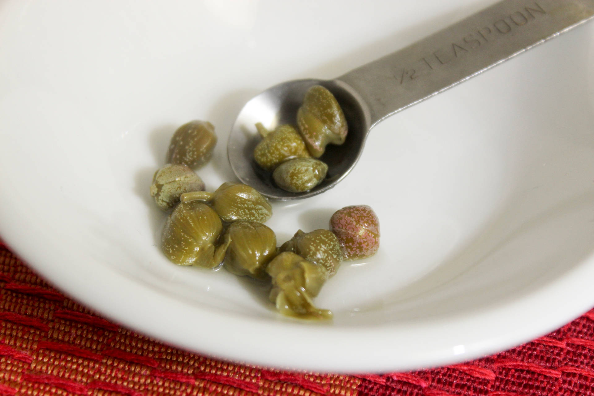 Capers In A Teaspoon On A White Bowl Wallpaper