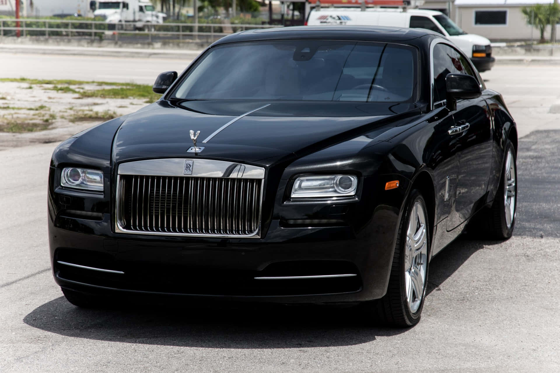 Caption: Elegant Rolls Royce Wraith Parked Under The City Lights Wallpaper