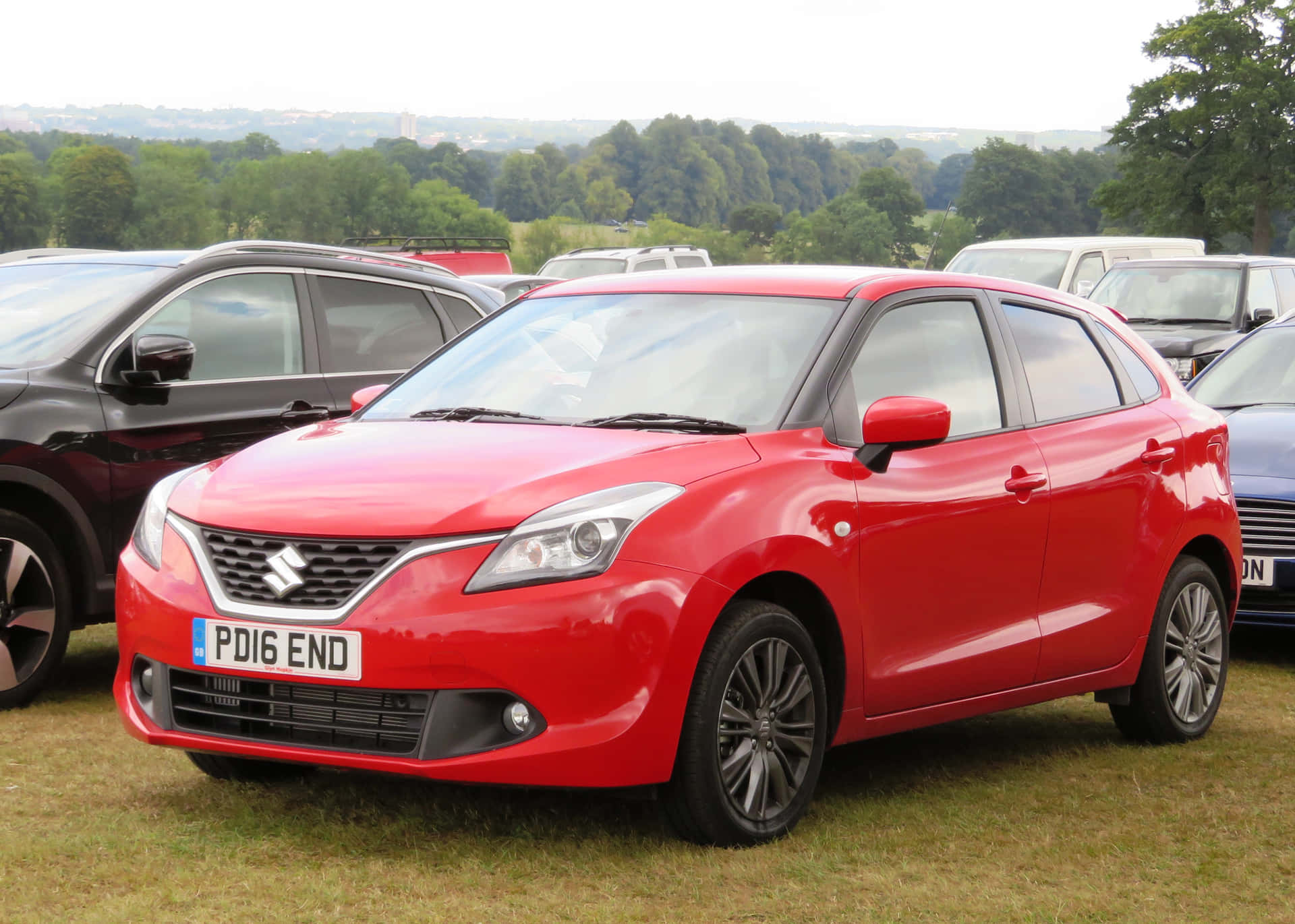 Caption: Sleek And Stylish Suzuki Baleno Cruising On A Road Wallpaper