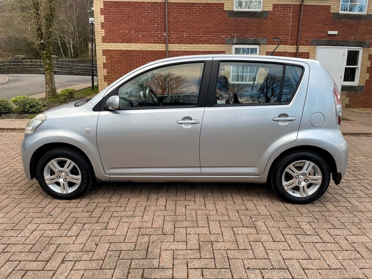 Caption: Sleek, Silver Daihatsu Yrv Under The Blue Sky Wallpaper