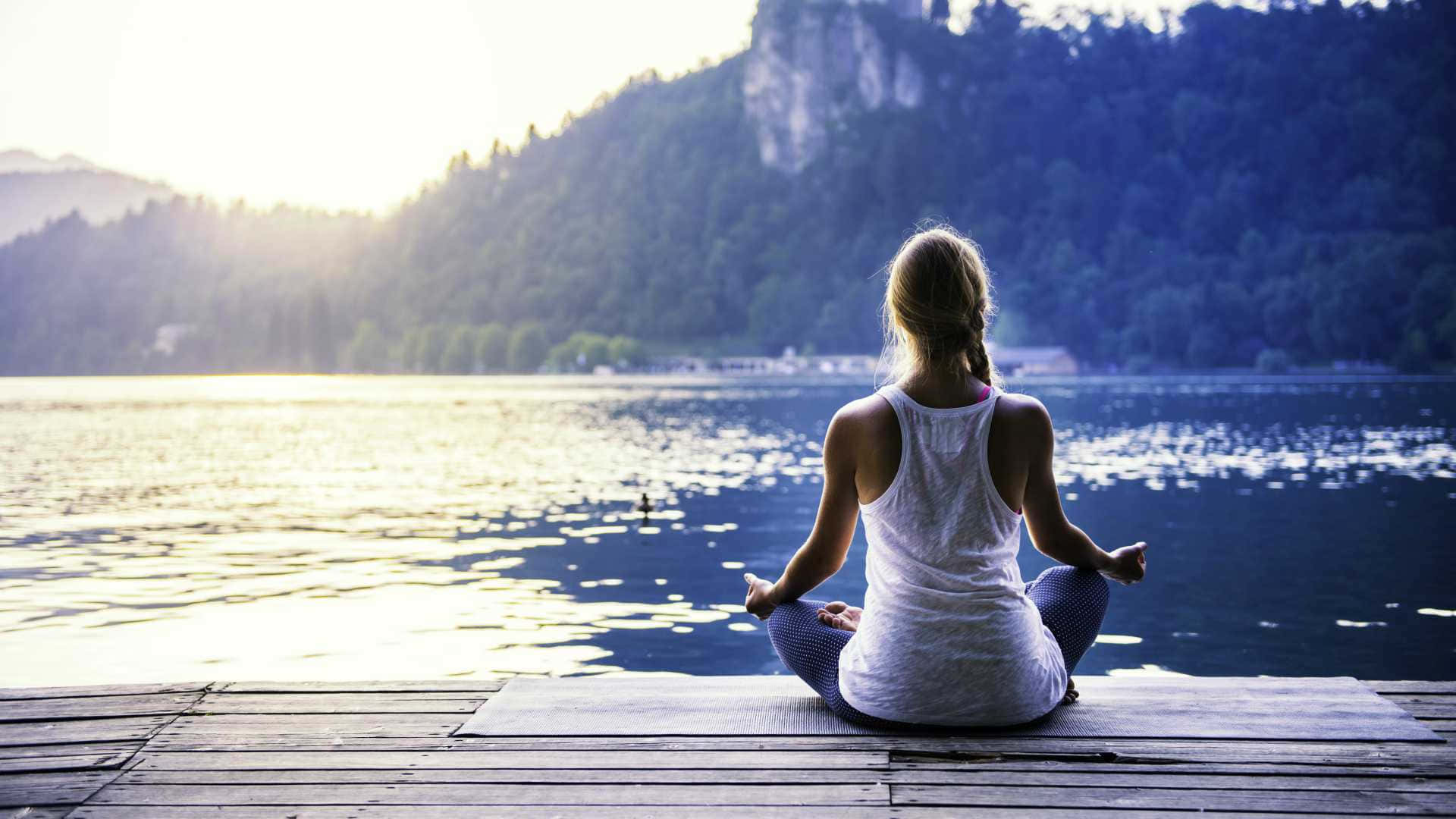 Capturing Zen: Woman Meditating In Lotus Position Wallpaper