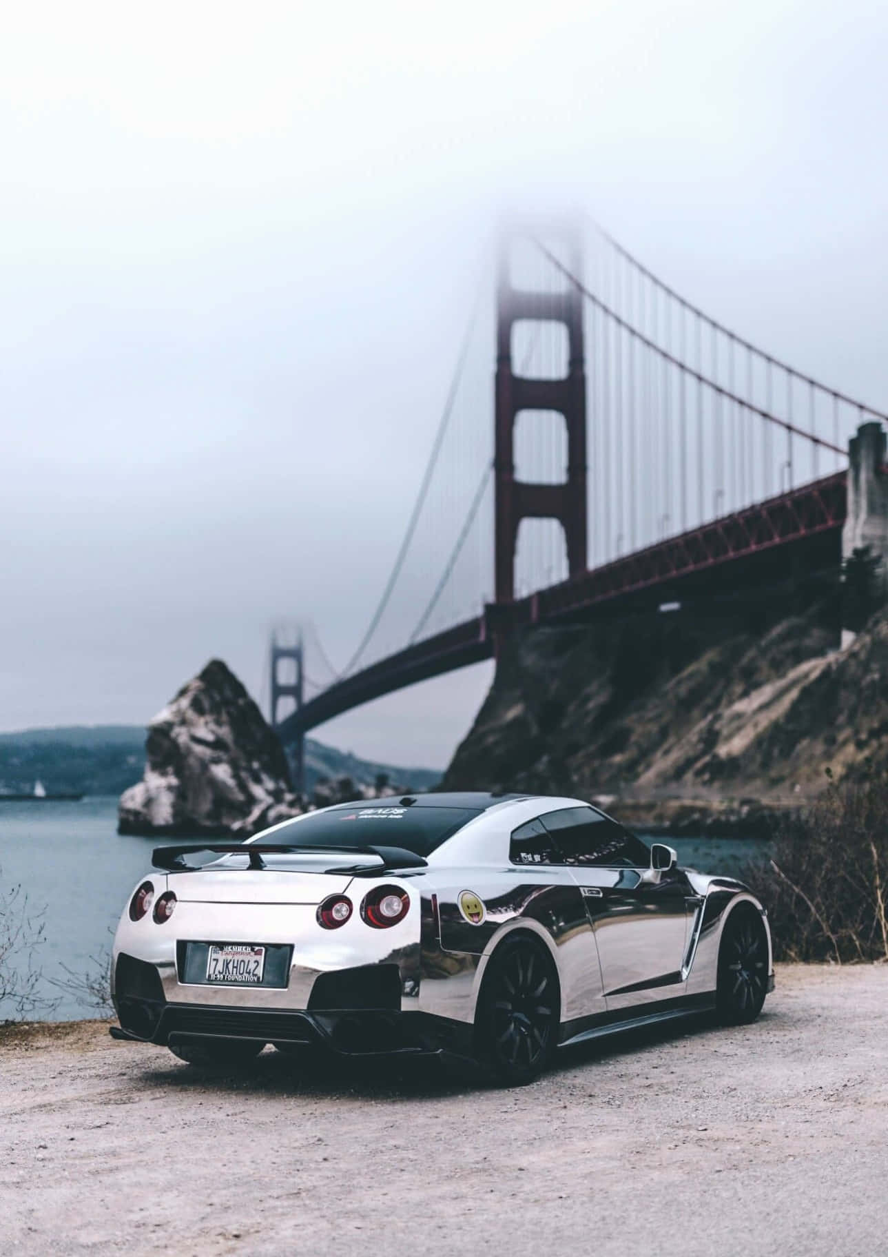 A Silver Car Is Parked In Front Of The Golden Gate Bridge Wallpaper