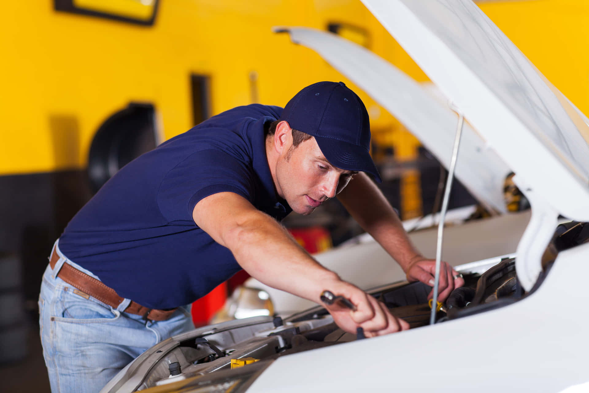 Professional mechanic fixing a car at the auto repair shop Wallpaper
