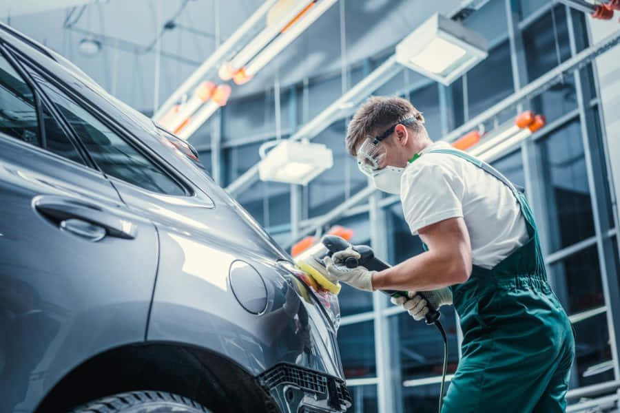 Professional mechanic repairing a car in a garage Wallpaper