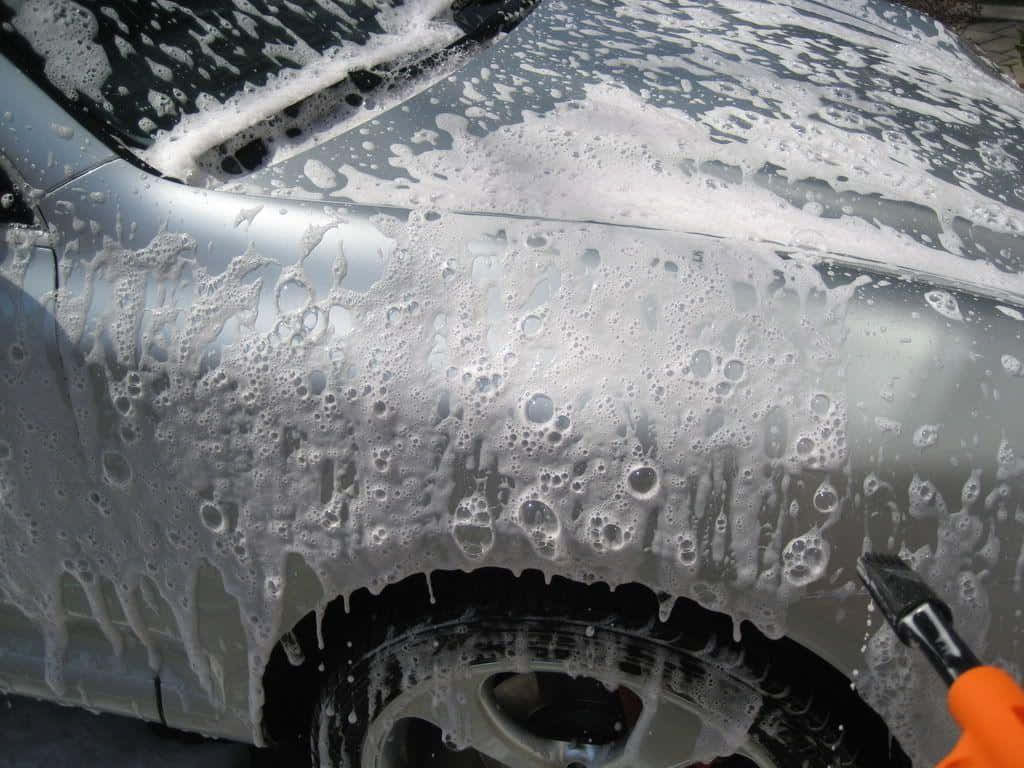 A Person Is Washing A Car With A Foam