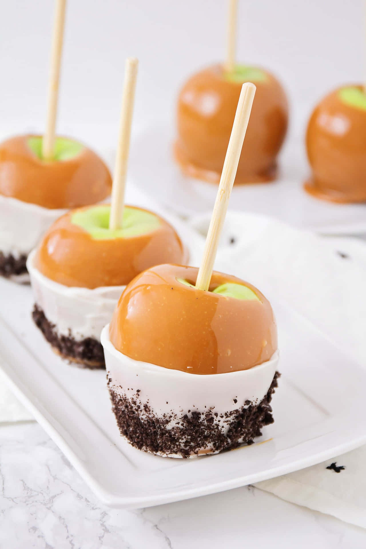 Caption: Delicious Caramel Apples on Rustic Wooden Table Wallpaper