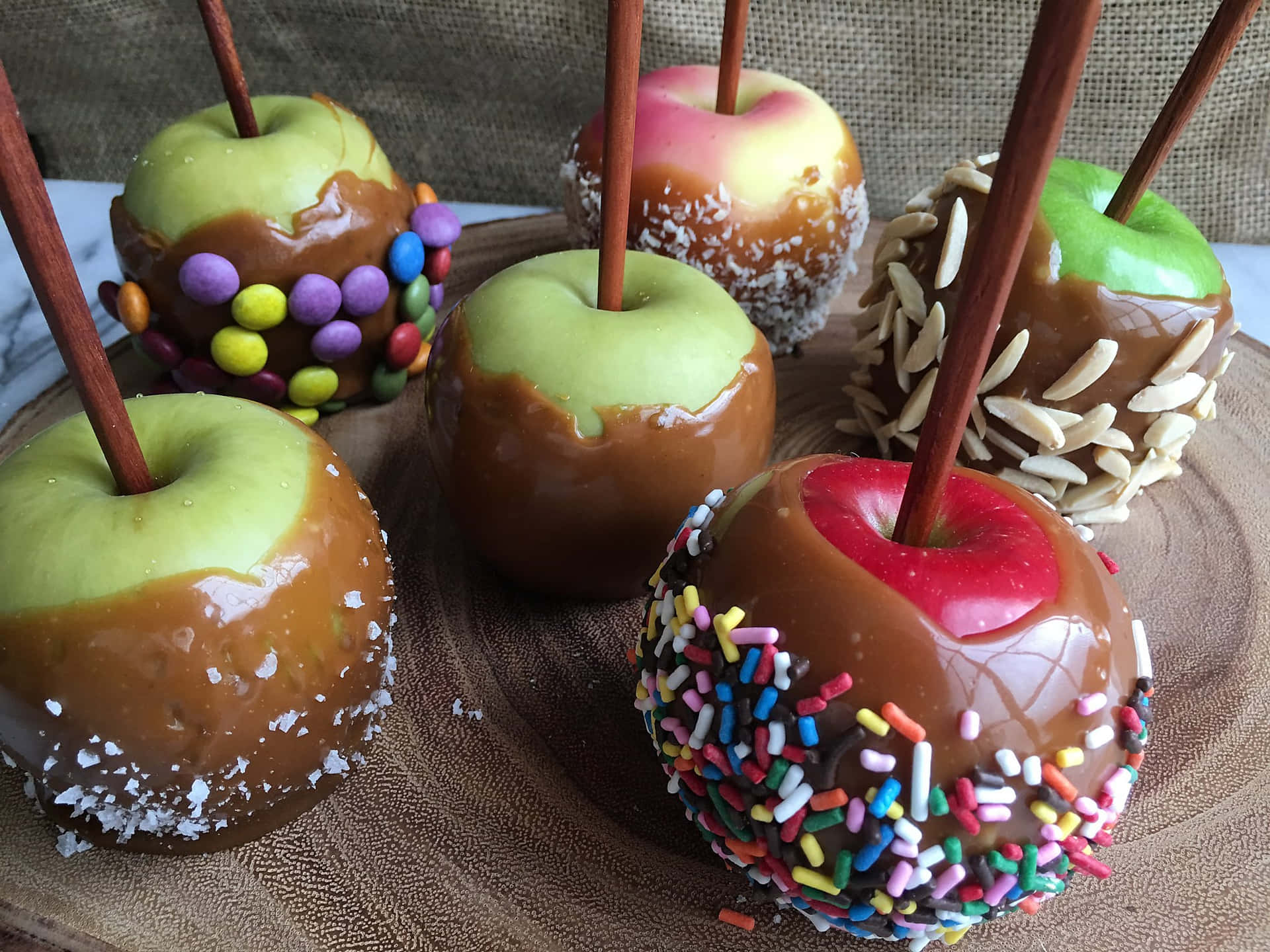 Tempting Caramel Apples on Wooden Table Wallpaper