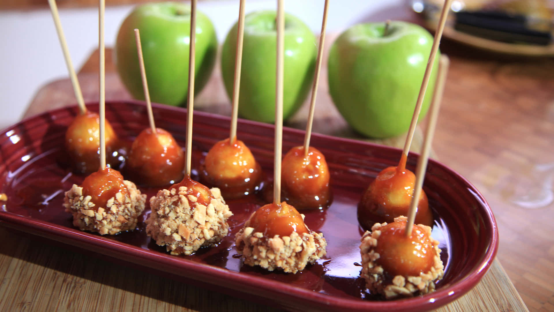 Gourmet Caramel Apples on a Rustic Wooden Table Wallpaper