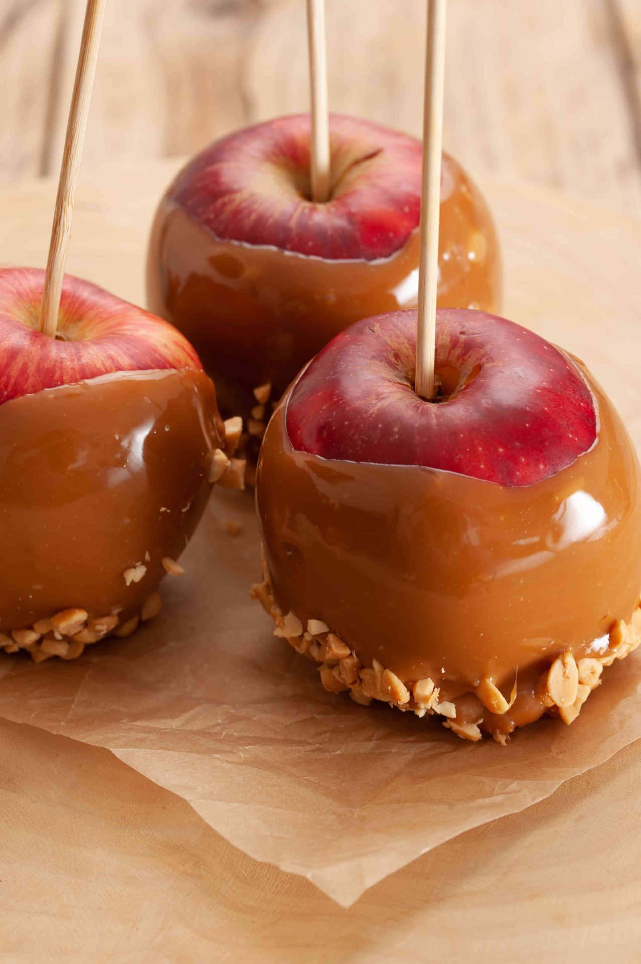 Mouth-watering Caramel Apples on a Rustic Wooden Table Wallpaper