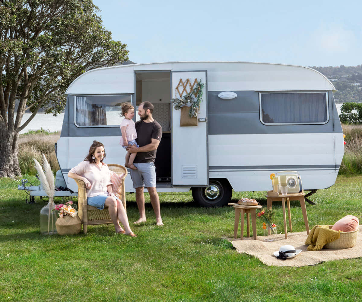 A Family Is Sitting In A Campervan On A Grassy Field