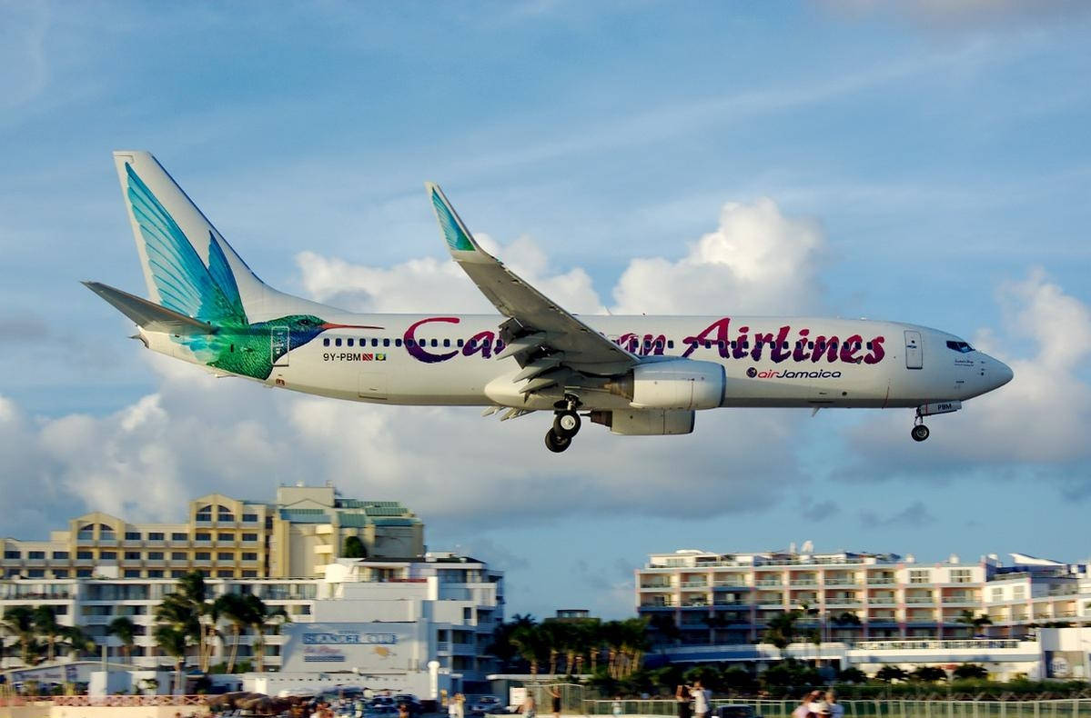 Caribbean Airlines Flying Above City Wallpaper