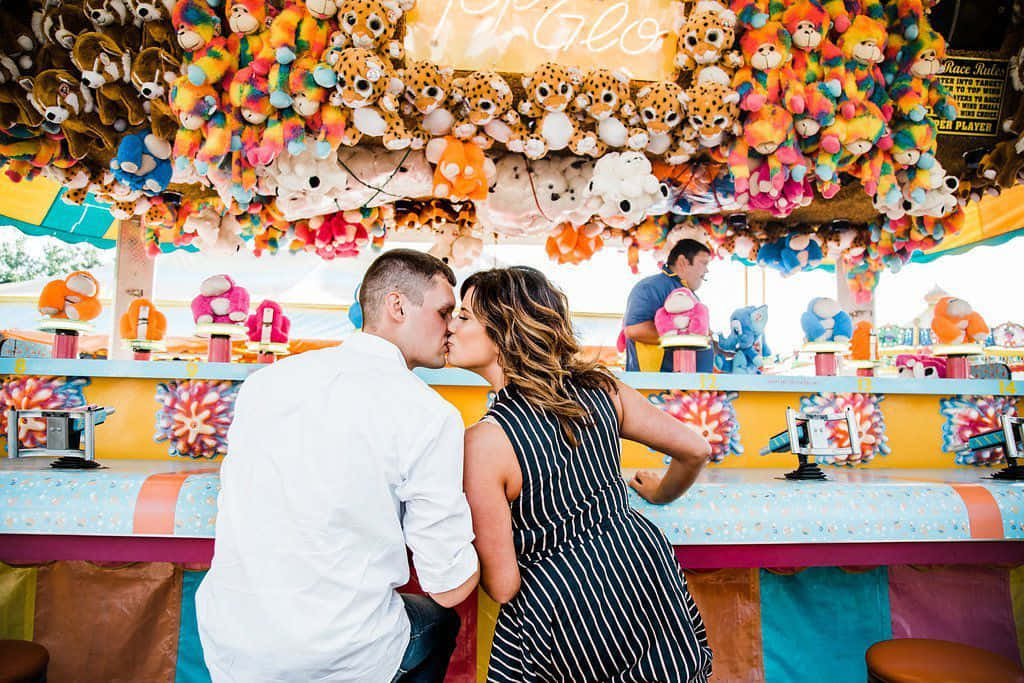 Kissing Couple In Front Of Carnival Booth Picture
