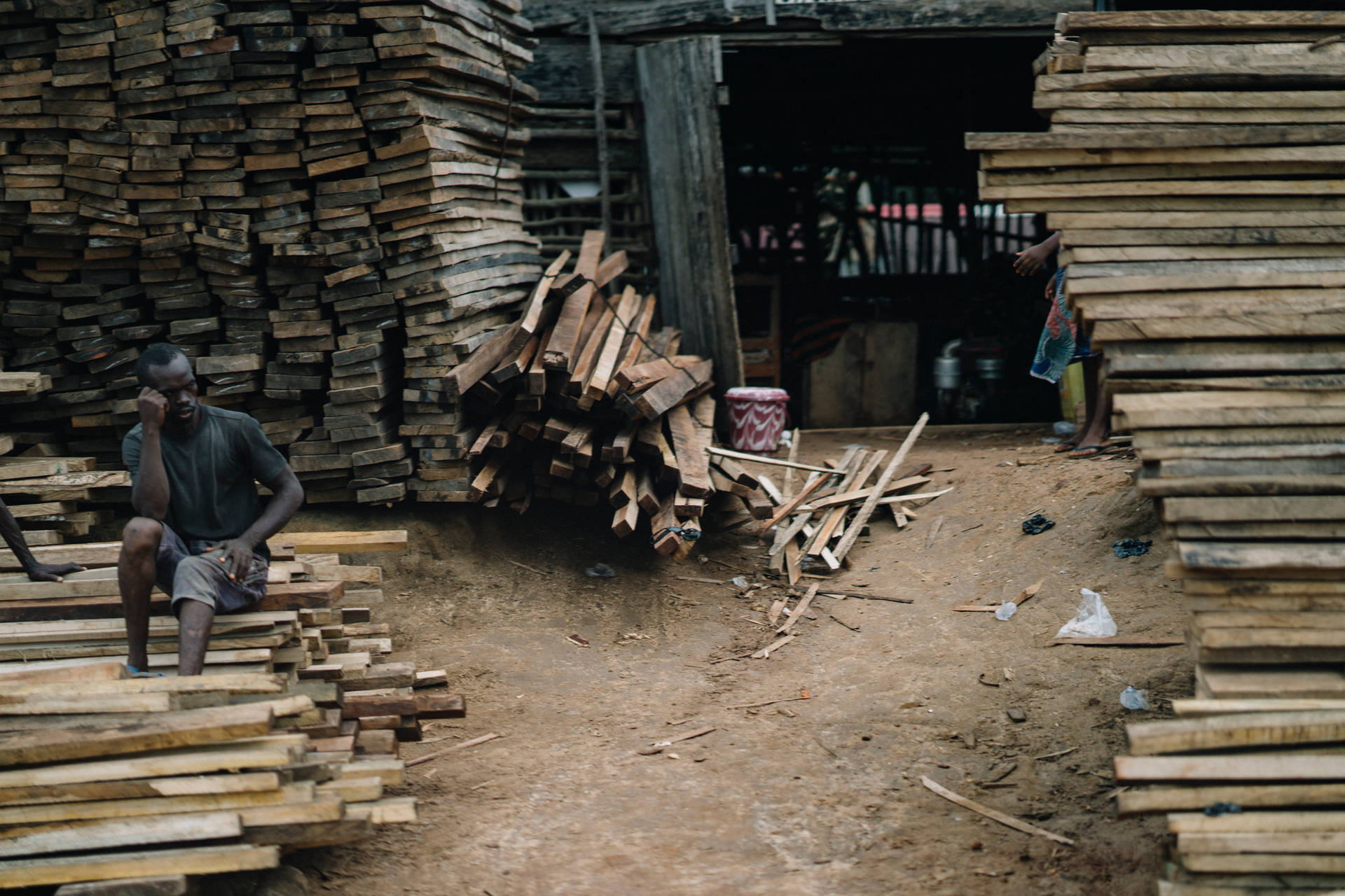 Carpenter With Stacks Of Wood In Sierra Leone Wallpaper