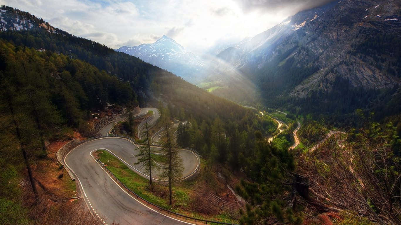 Cars Passing By A Winding Mountain Road Wallpaper