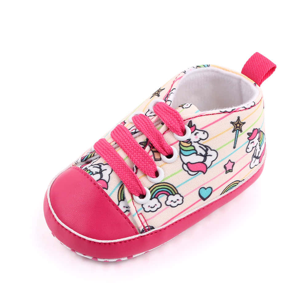 A Pink And White Baby Shoe With Unicorns On It