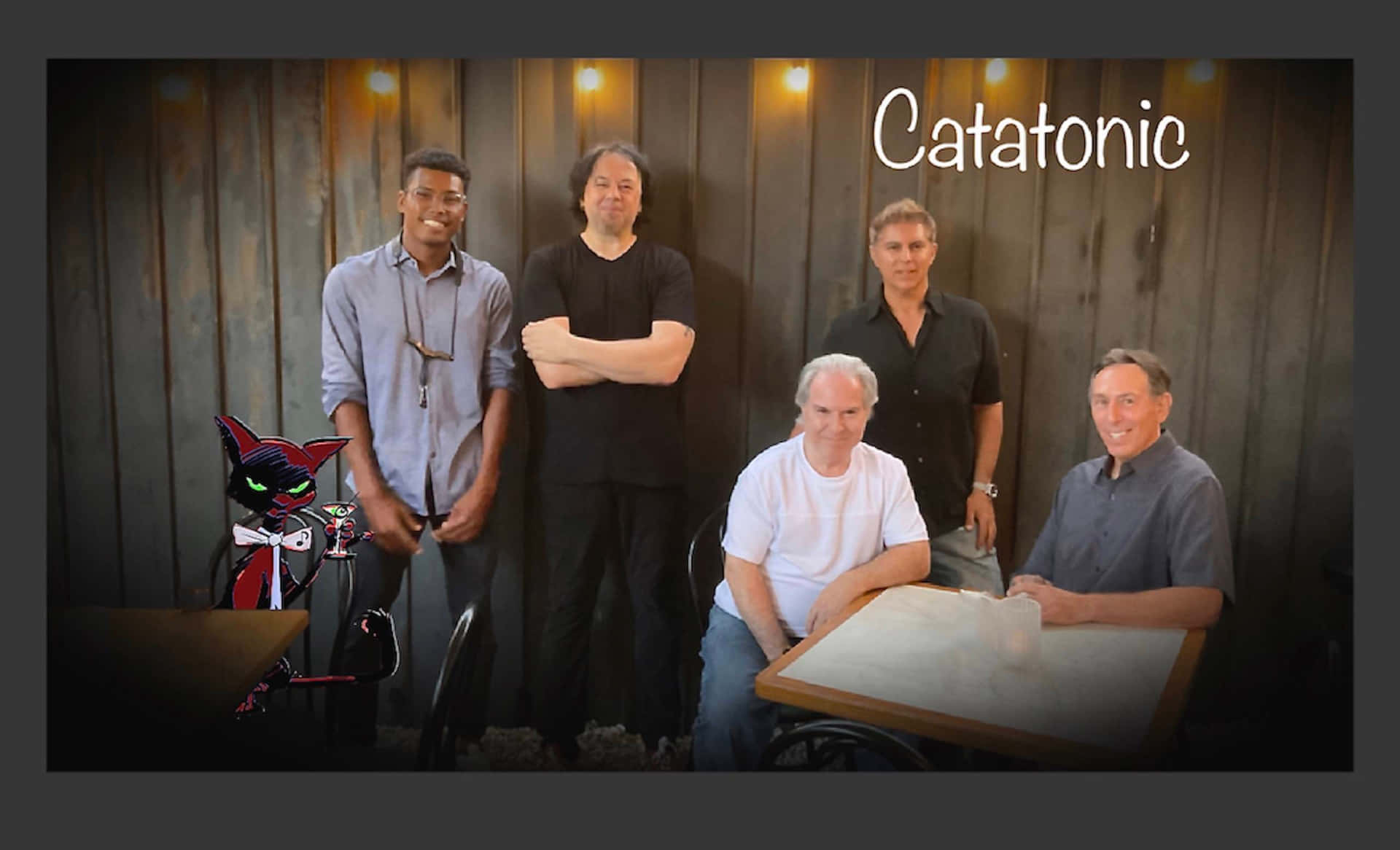Catatonic - A Group Of Men Standing In Front Of A Table Wallpaper