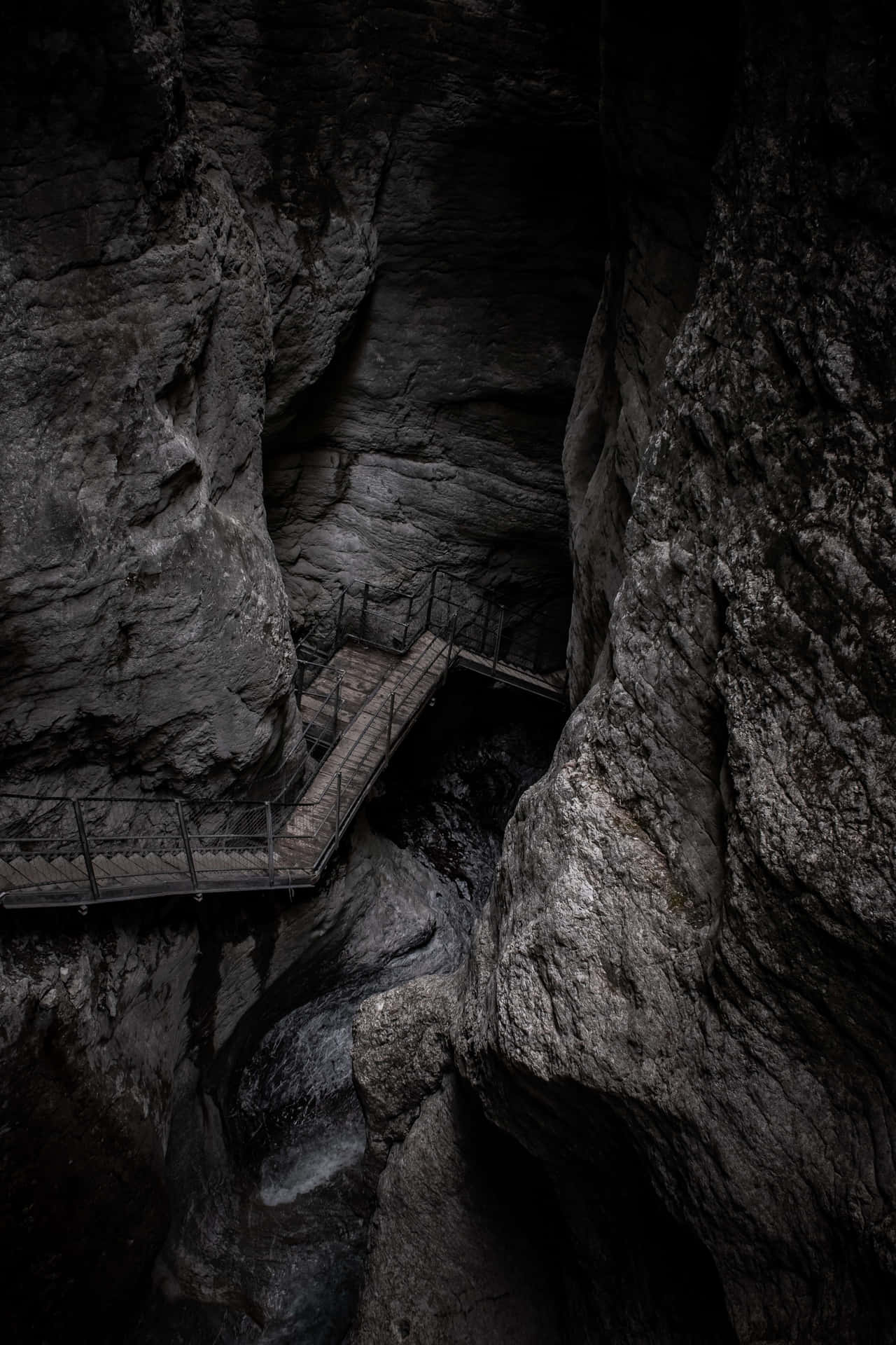A Wooden Walkway In A Dark Canyon