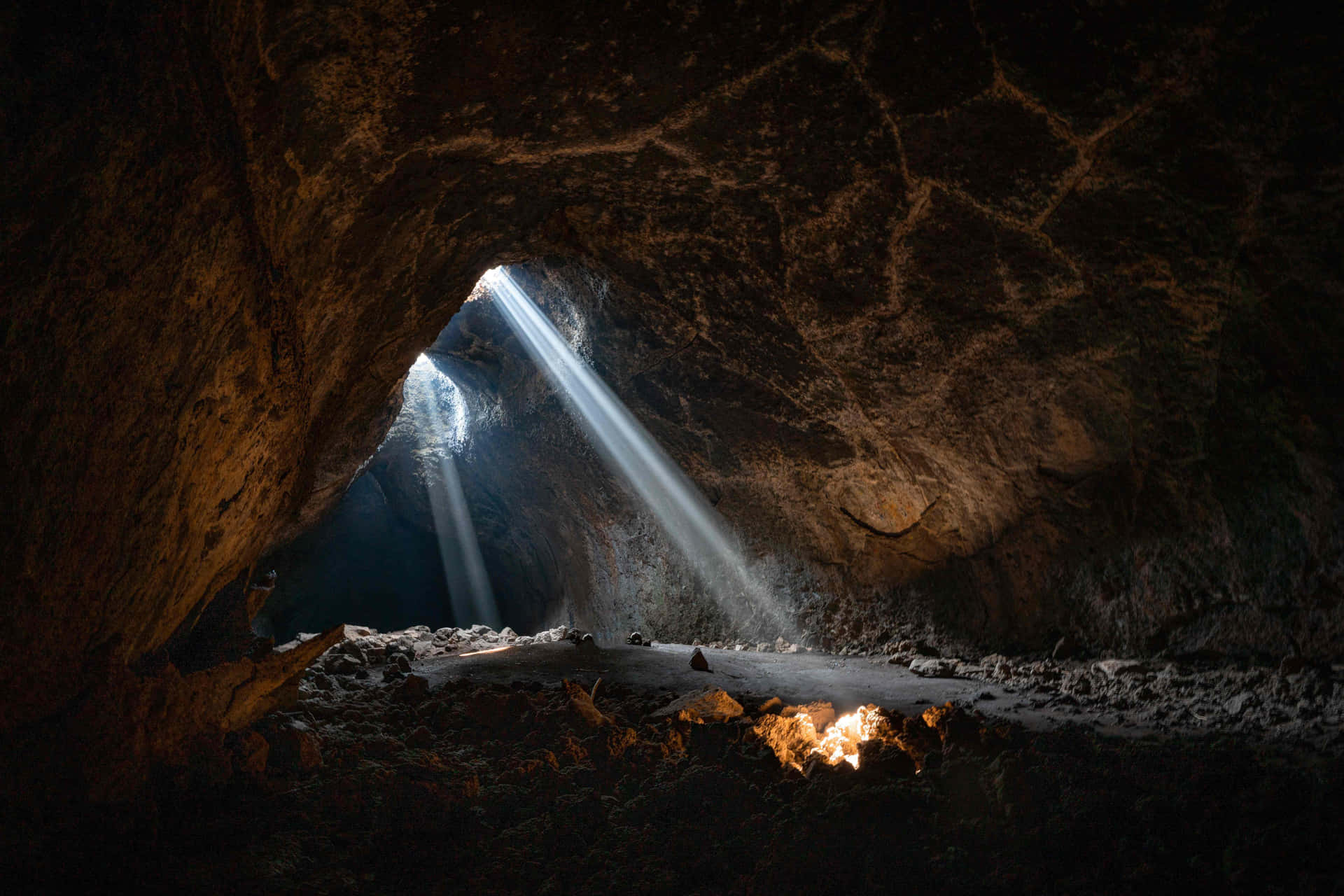 A Cave With A Fire And Sunlight Shining Through It