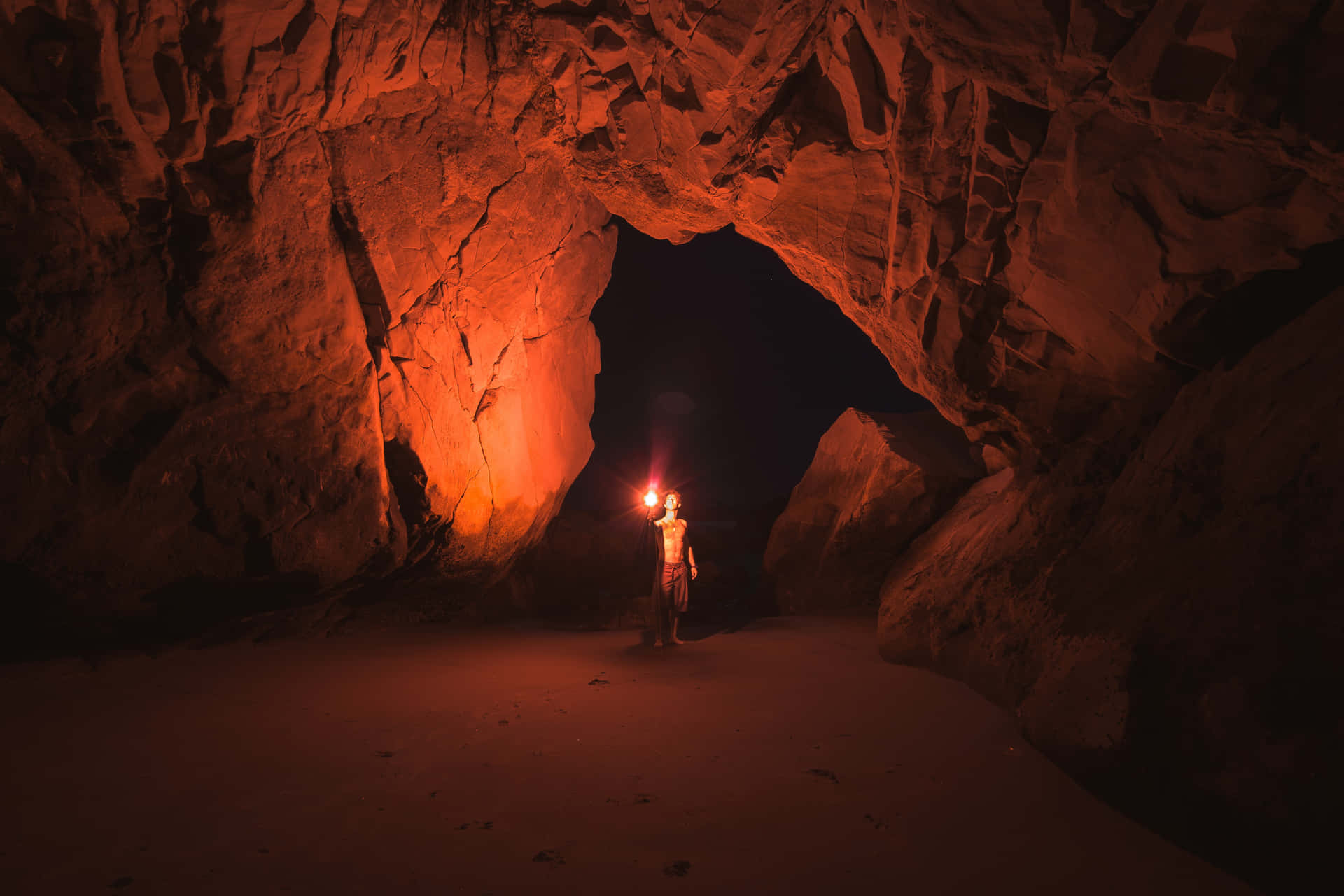 A Man Standing In A Cave With A Torch
