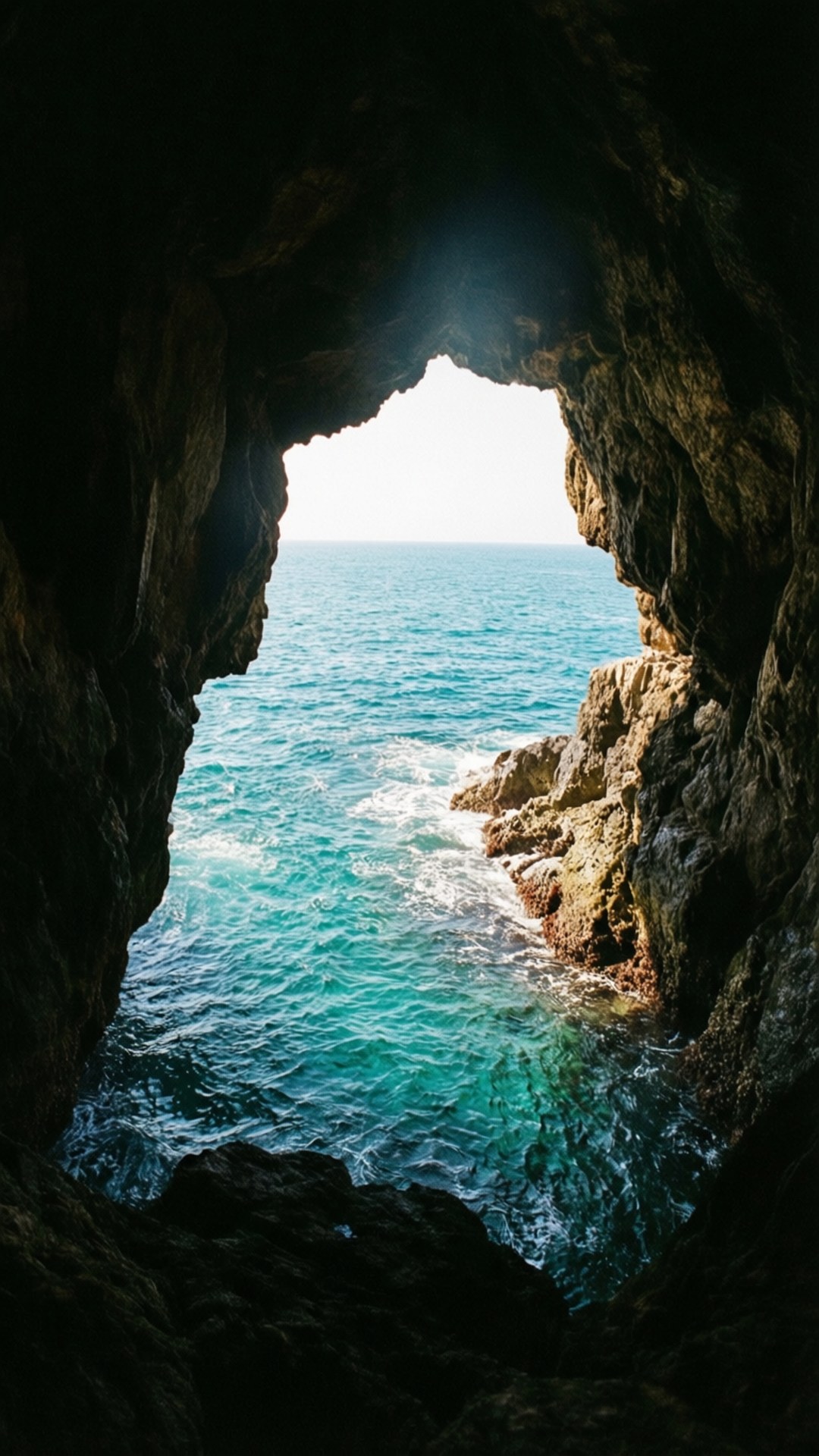 Ocean view through a cave opening with turquoise water.