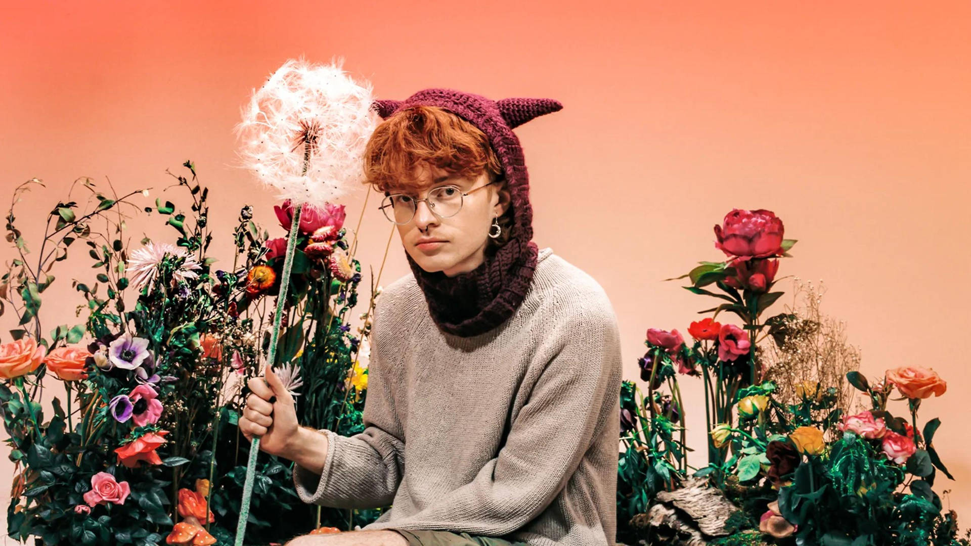Einmann Mit Roten Haaren Sitzt Auf Einem Blumenbeet. Wallpaper