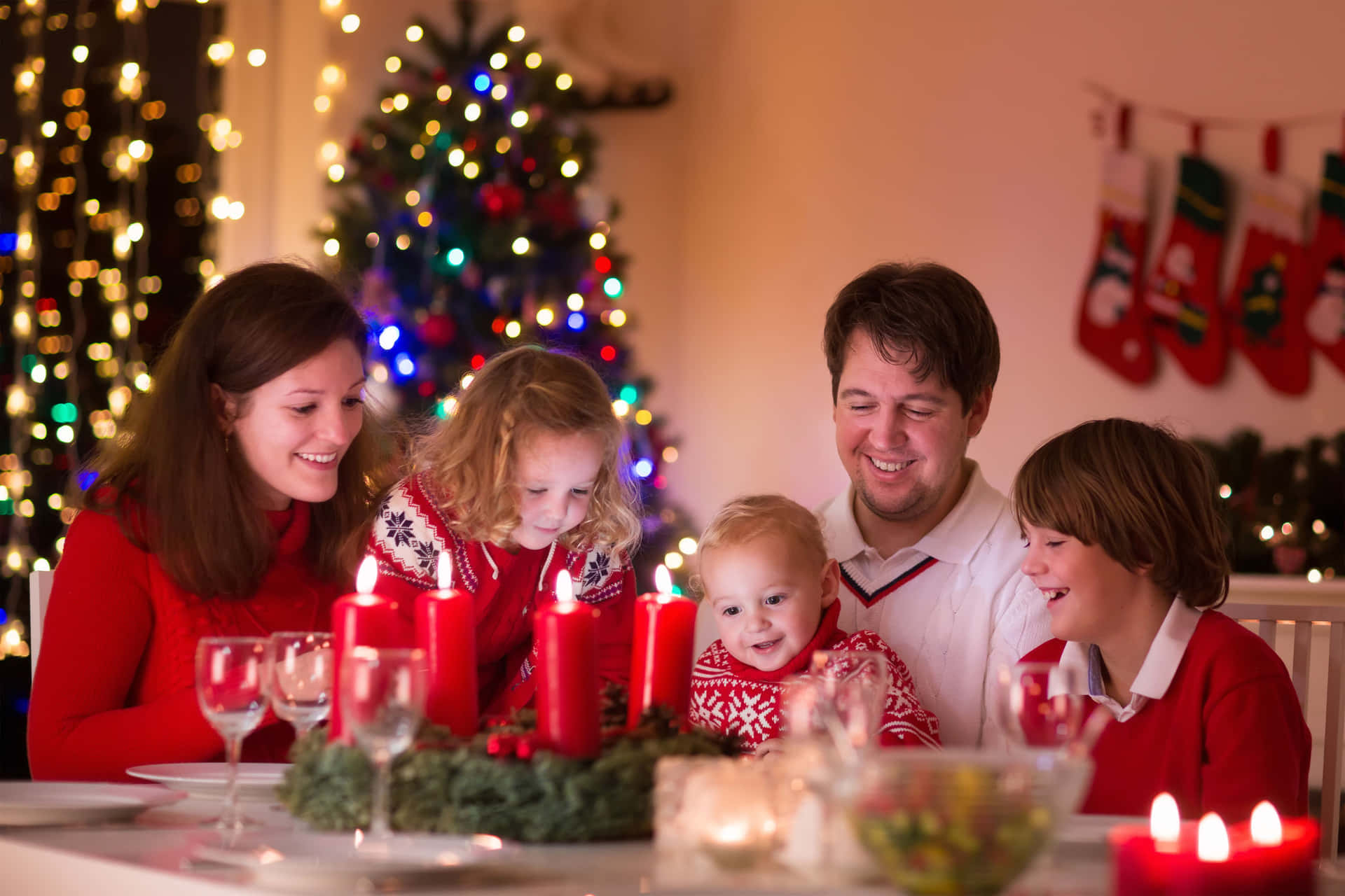 Familiesitzt An Einem Tisch Mit Weihnachtslichtern.