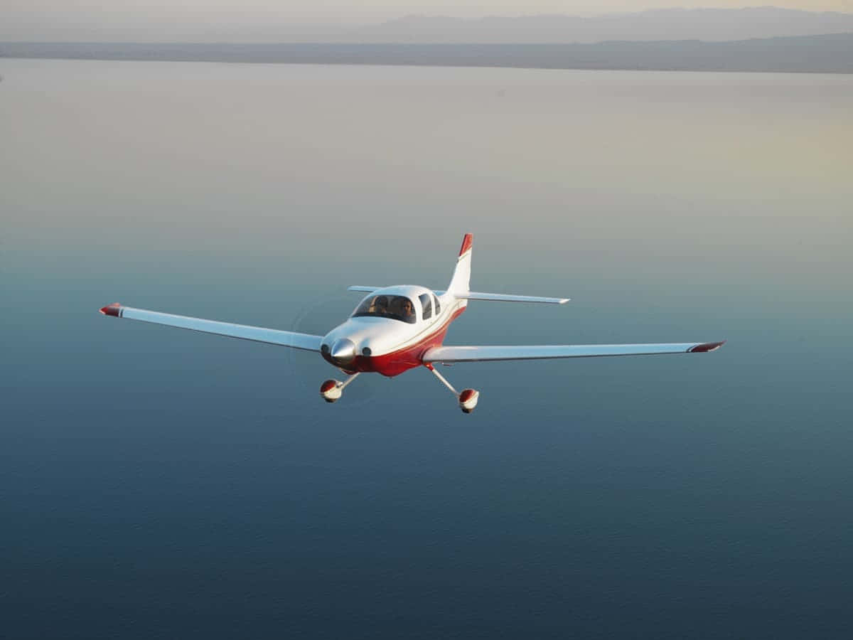 Cesna 400 Small Airplane Gliding Over Water Wallpaper