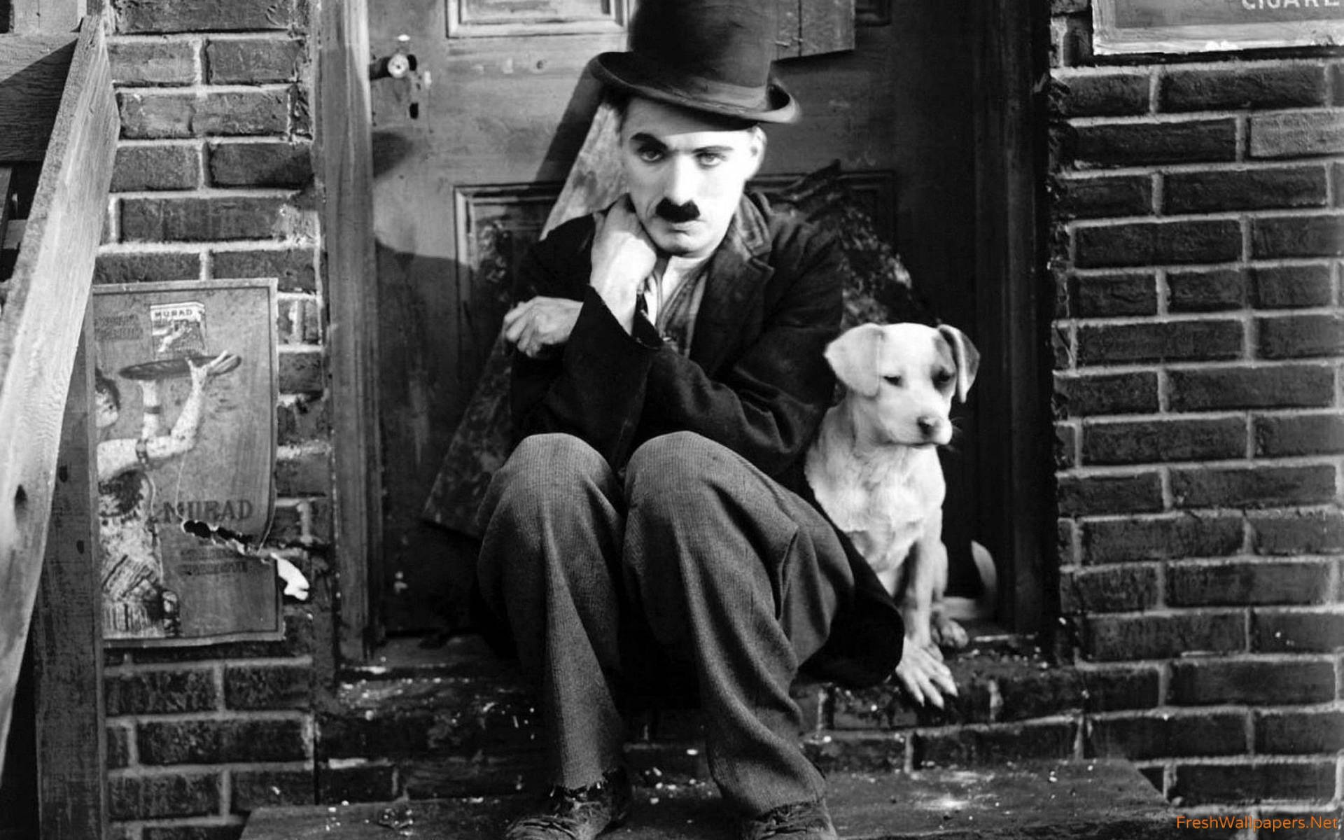 Charlie Chaplin sitting with a small puppy outside a brick building wallpaper