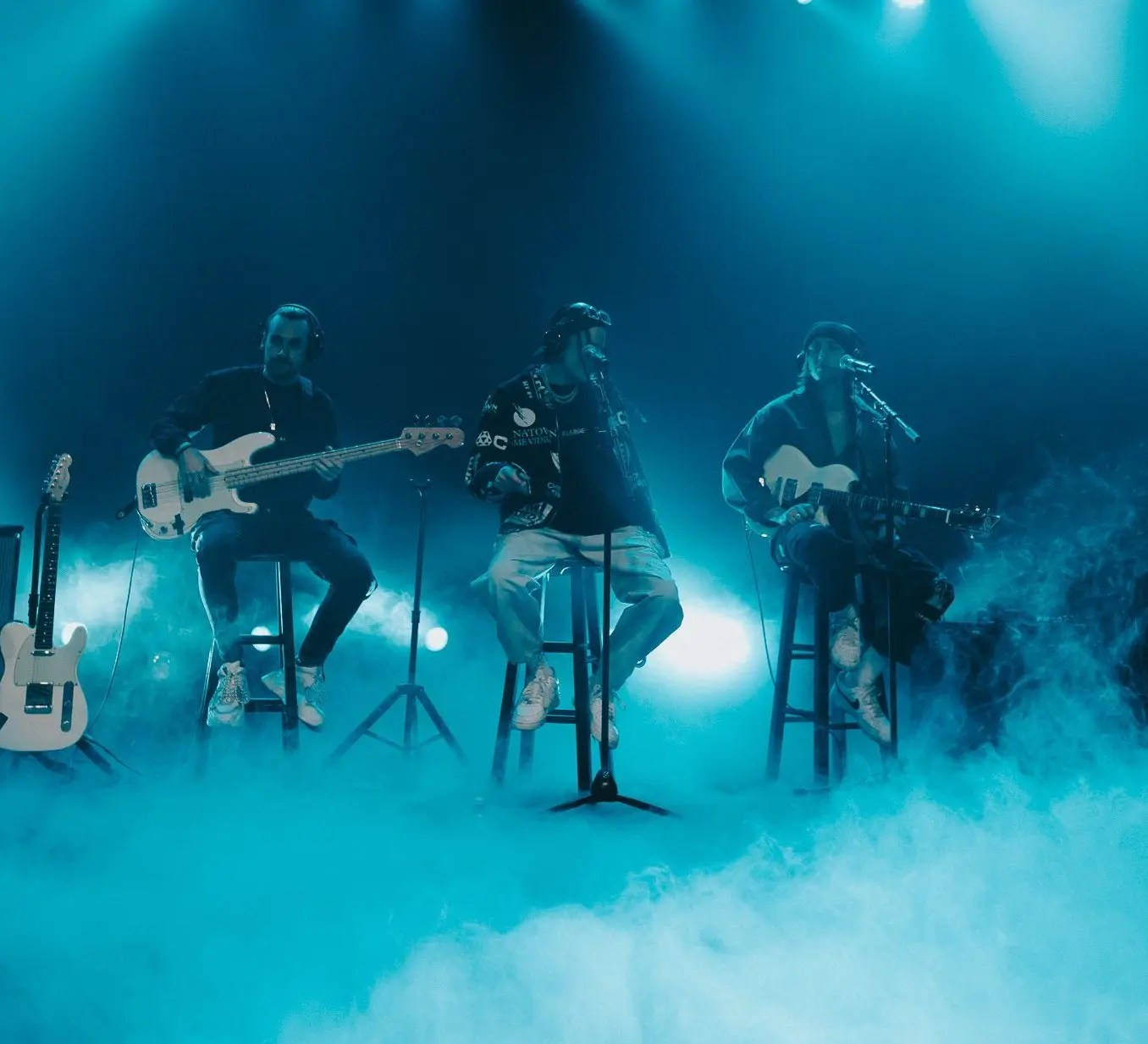 En gruppe mennesker på scenen med guitarer og røg Wallpaper