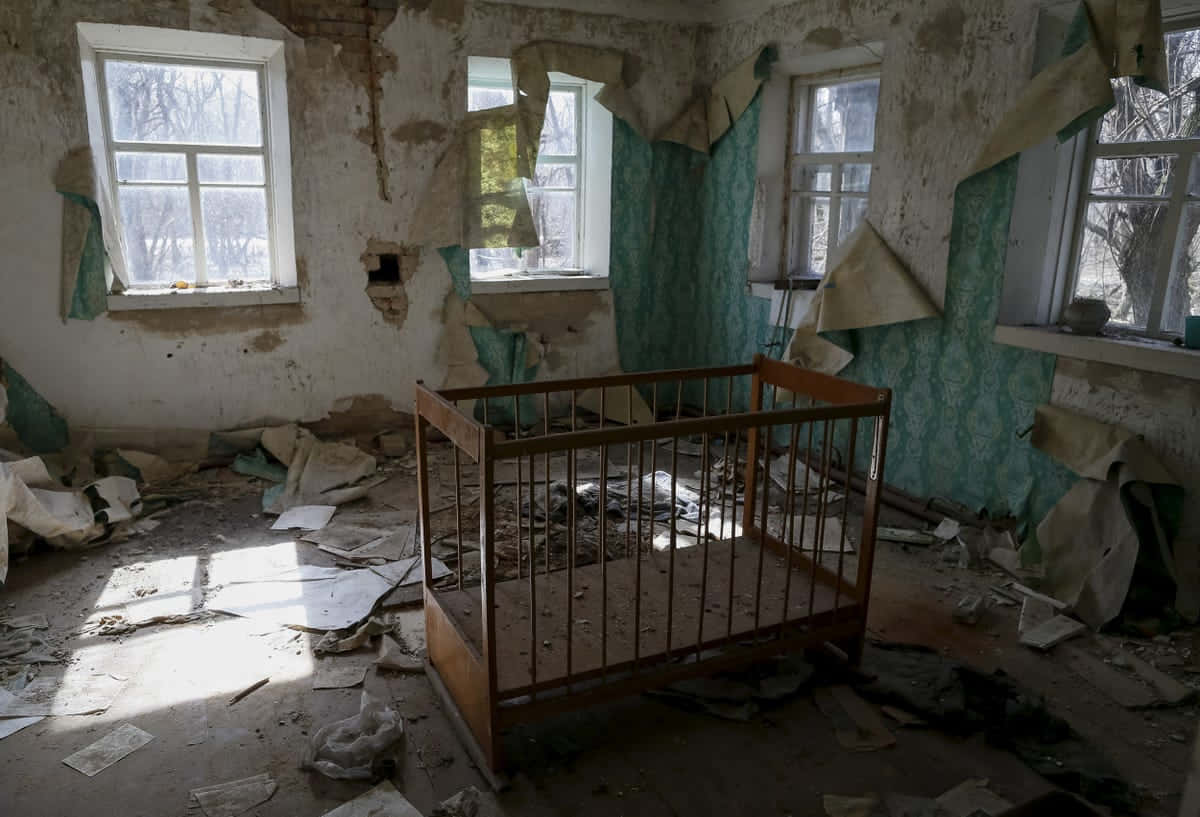 Einverlassenes Zimmer Mit Einem Kinderbett Und Kaputten Fenstern.