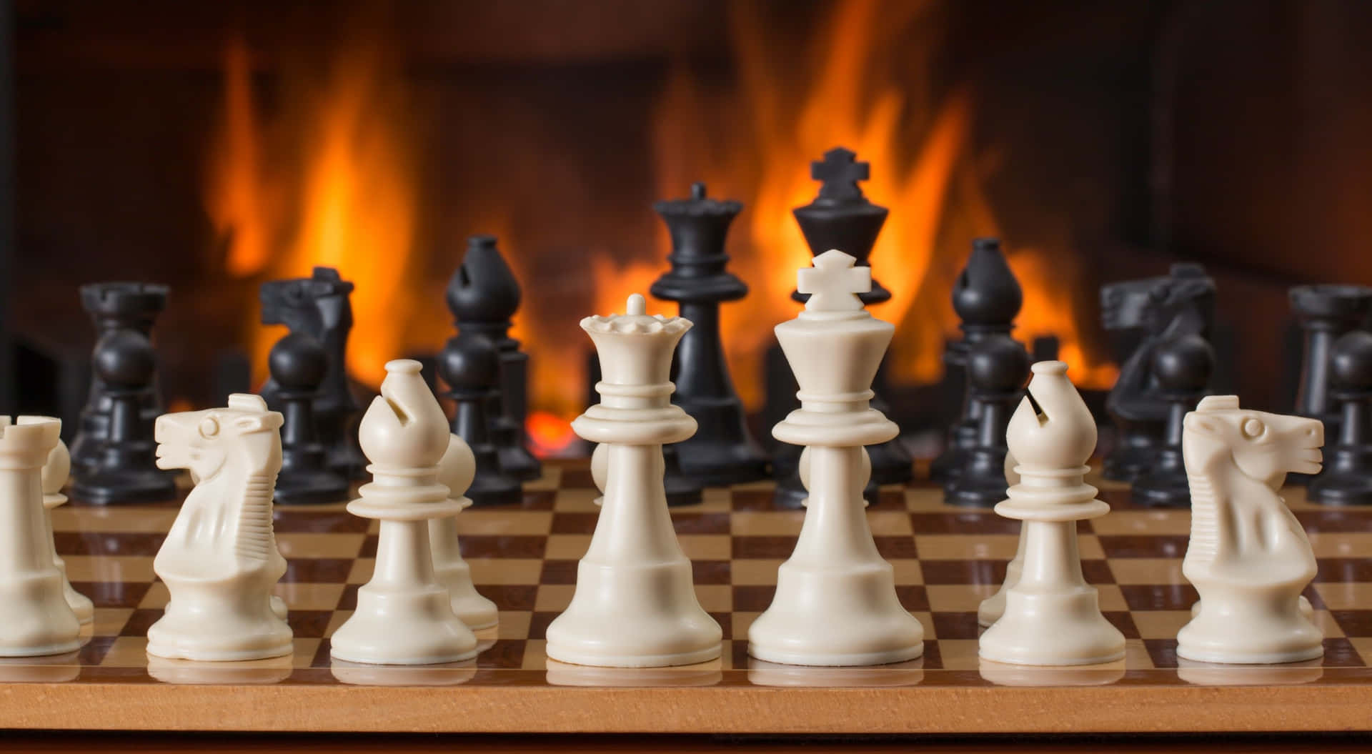 Chess Pieces On A Wooden Board In Front Of A Fireplace