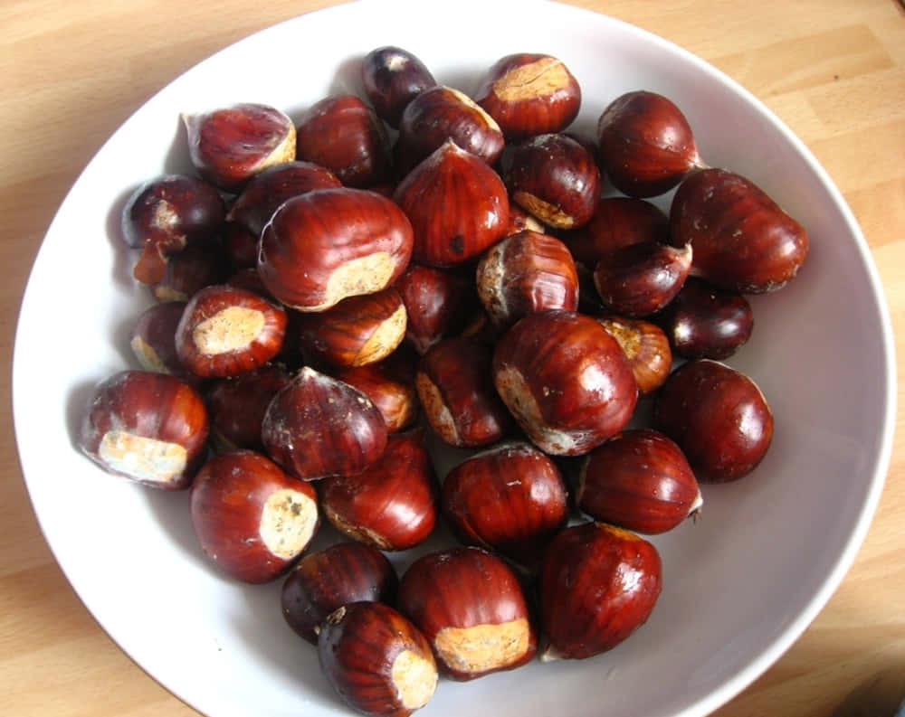 Caption: Fresh Chestnuts on a Rustic Wooden Table Wallpaper