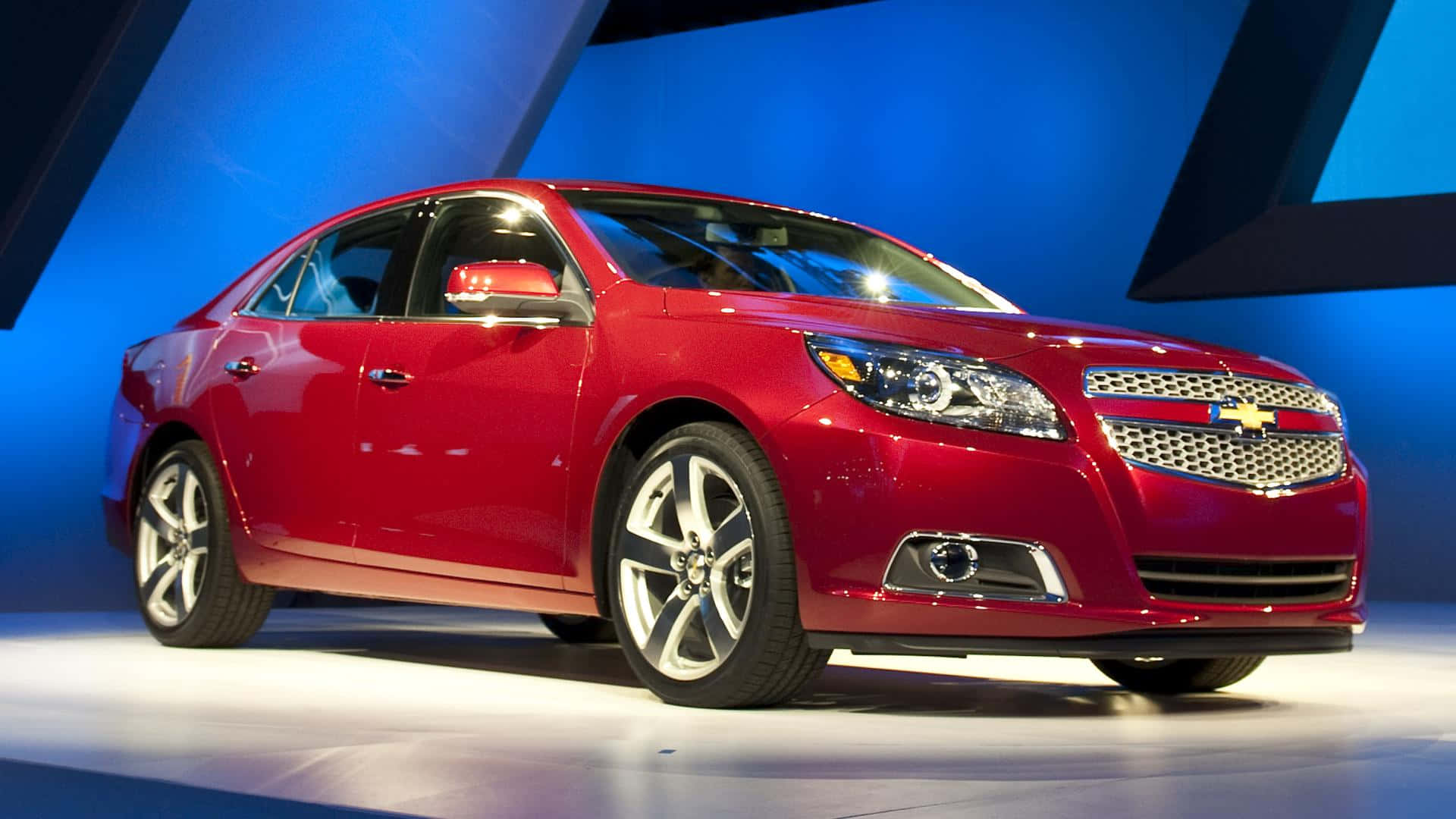 A Red Chevrolet Malibu Is On Display At An Auto Show Wallpaper