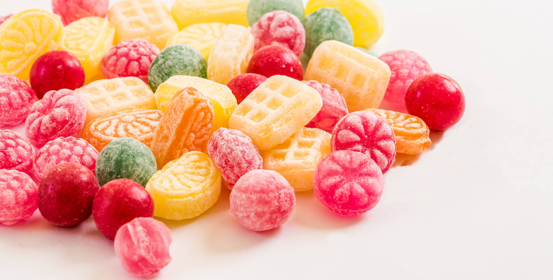 Søde frugtformede konfekter drysset over et blødt pink baggrund. Wallpaper