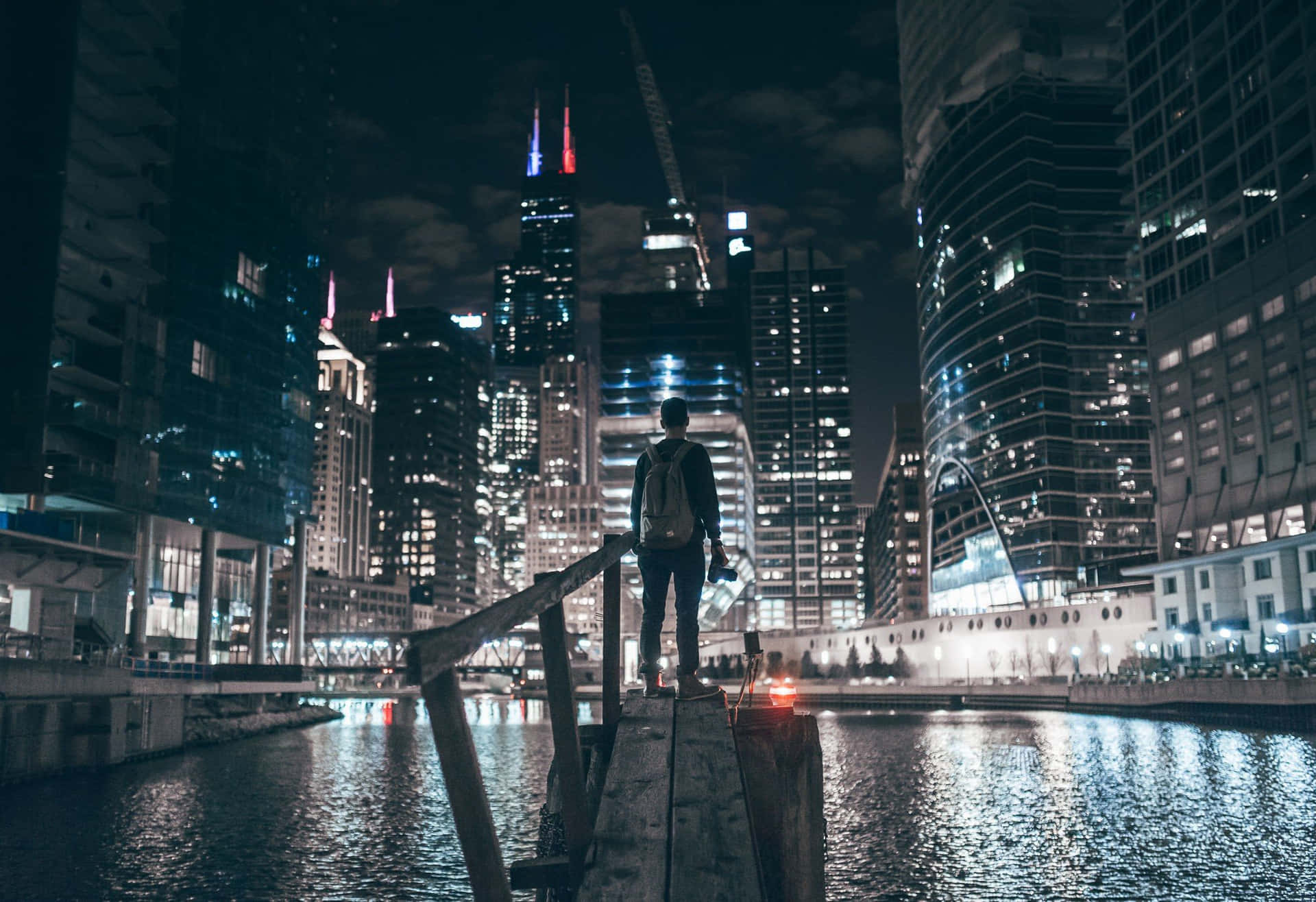 En mand står på en kaj om natten i byen. Wallpaper