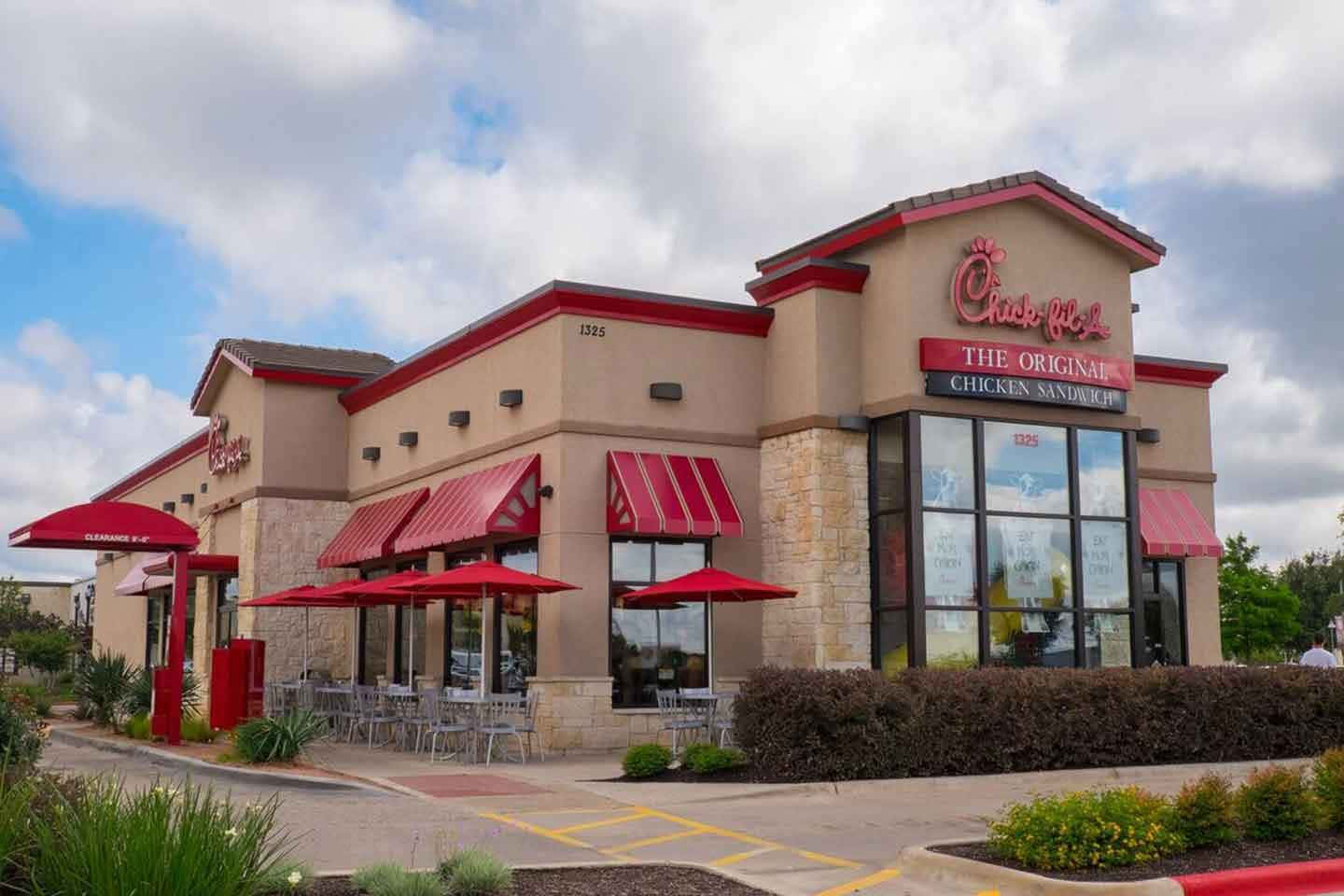 A Restaurant With Red Awnings And Chairs